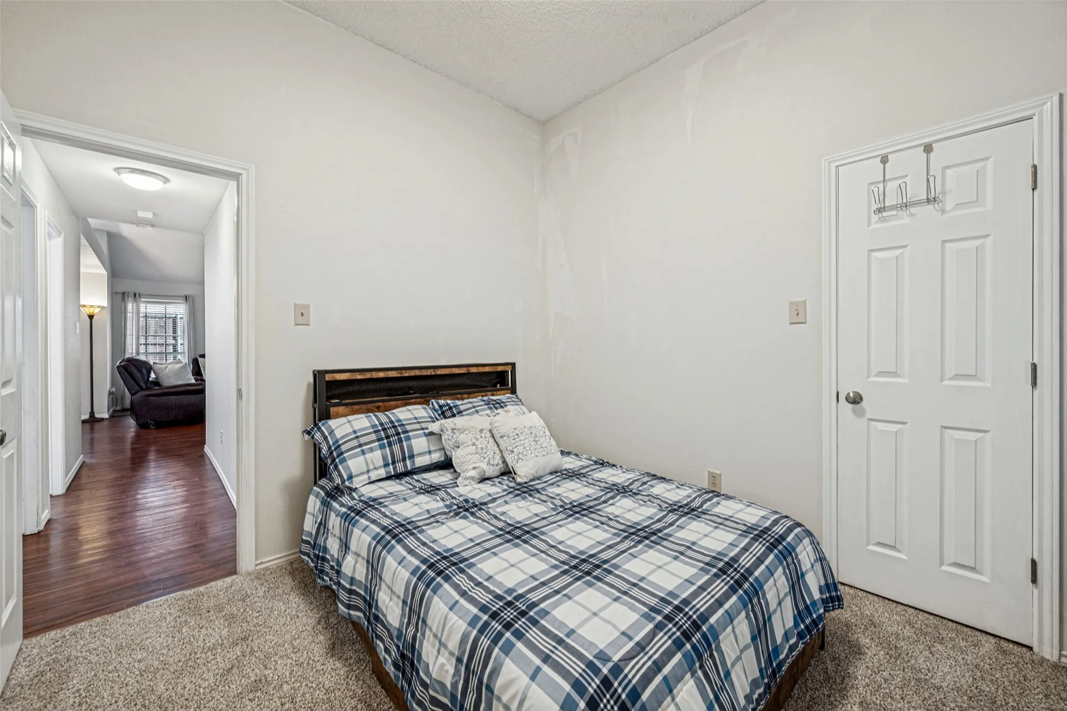 Carpeted room with a paneled door and a wood-finish headboard