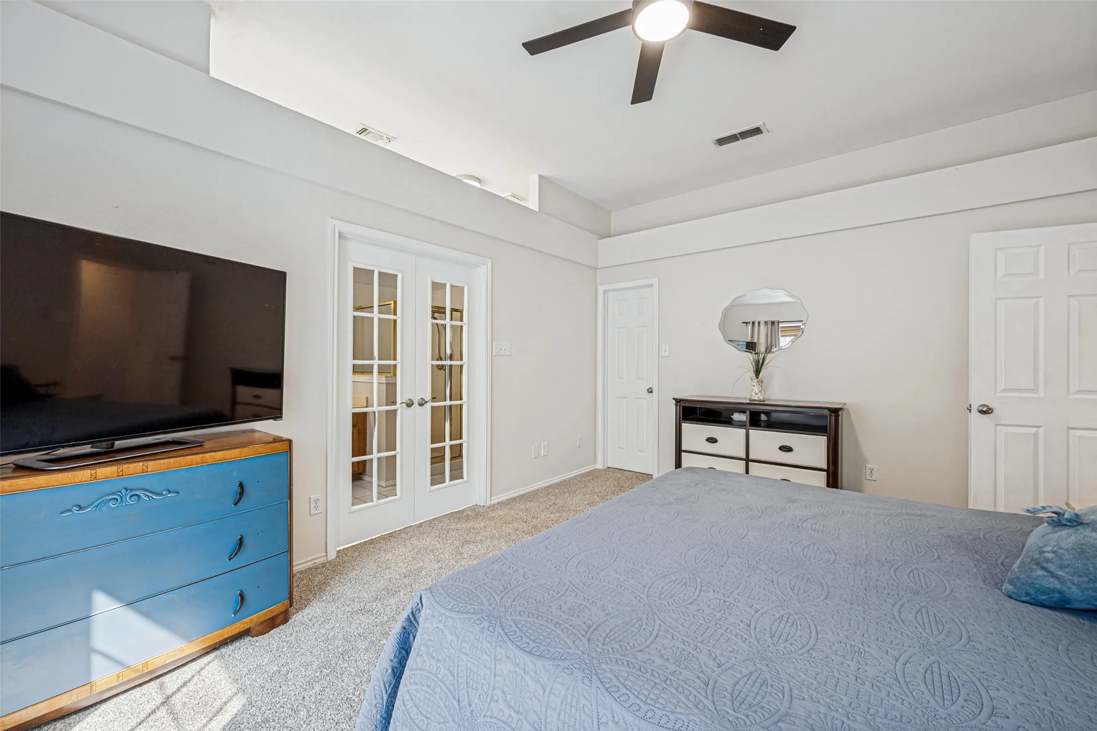 Recessed ceiling with an overhead fan, plush carpet flooring, and white French doors