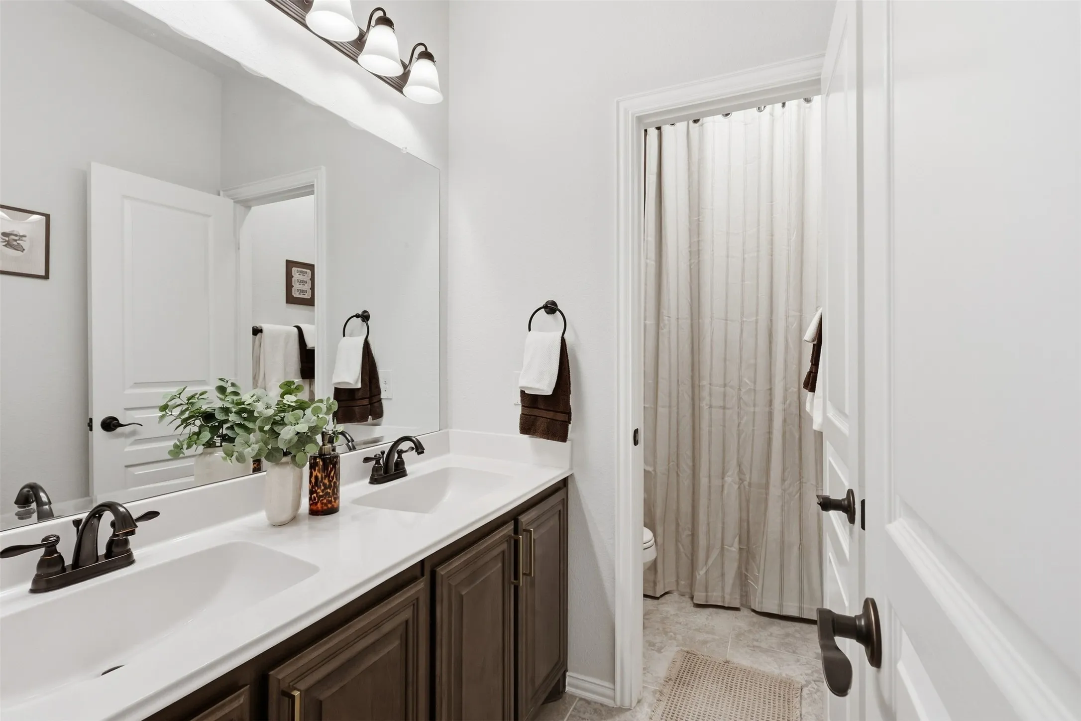 Guest bath upstairs with double vanities and shower/tub combo with privacy door