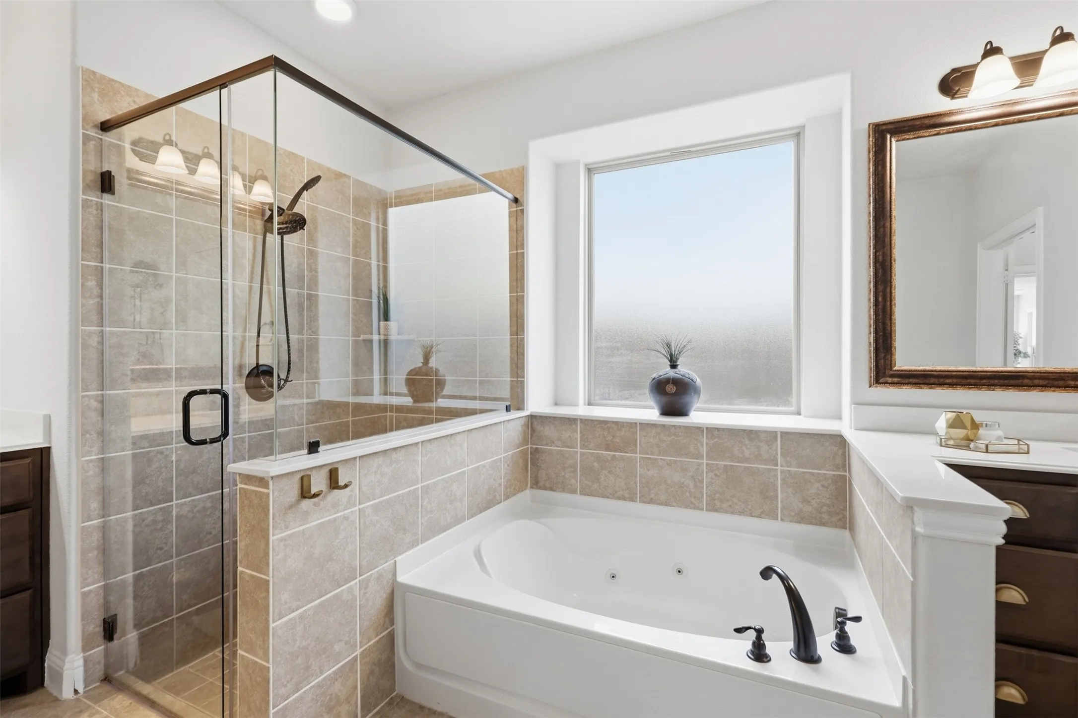 Glass-enclosed shower with tiled walls, corner soaking tub with dark-finish fixtures, and a large window above the tub