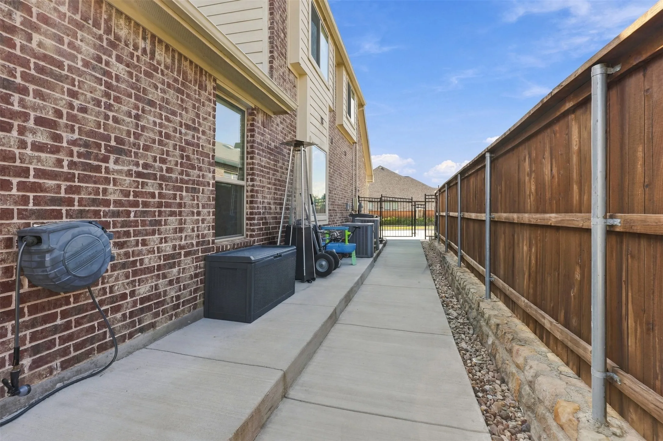 Brick exterior with concrete walkway, wood privacy fence, and stone retaining wall