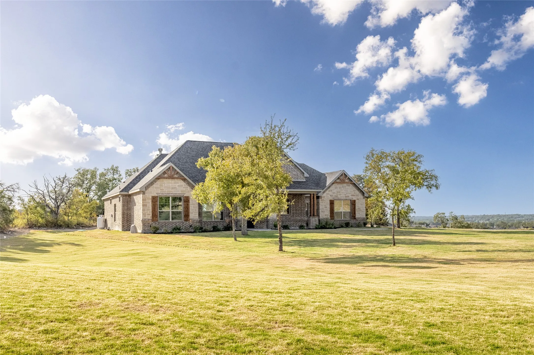 Expansive exterior with a brick and stone facade, contrasting dark roof, and decorative wooden shutters