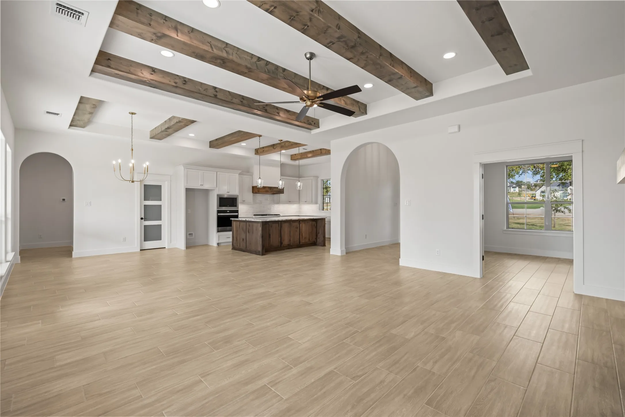 Tray ceiling with wood-finish beams, recessed lighting, and a ceiling fan
