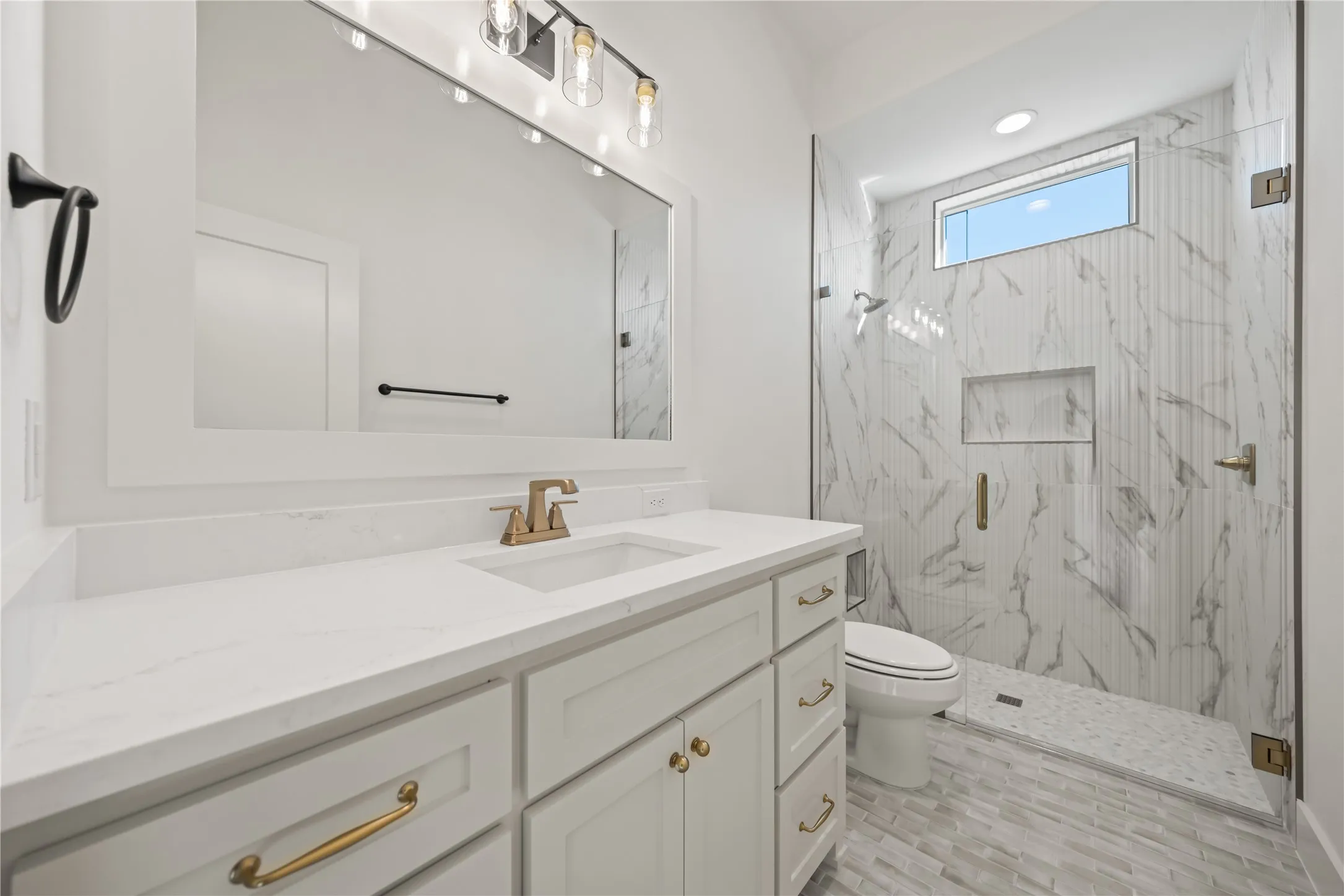 White shaker-style vanity with brass hardware, quartz countertop, and integrated sink