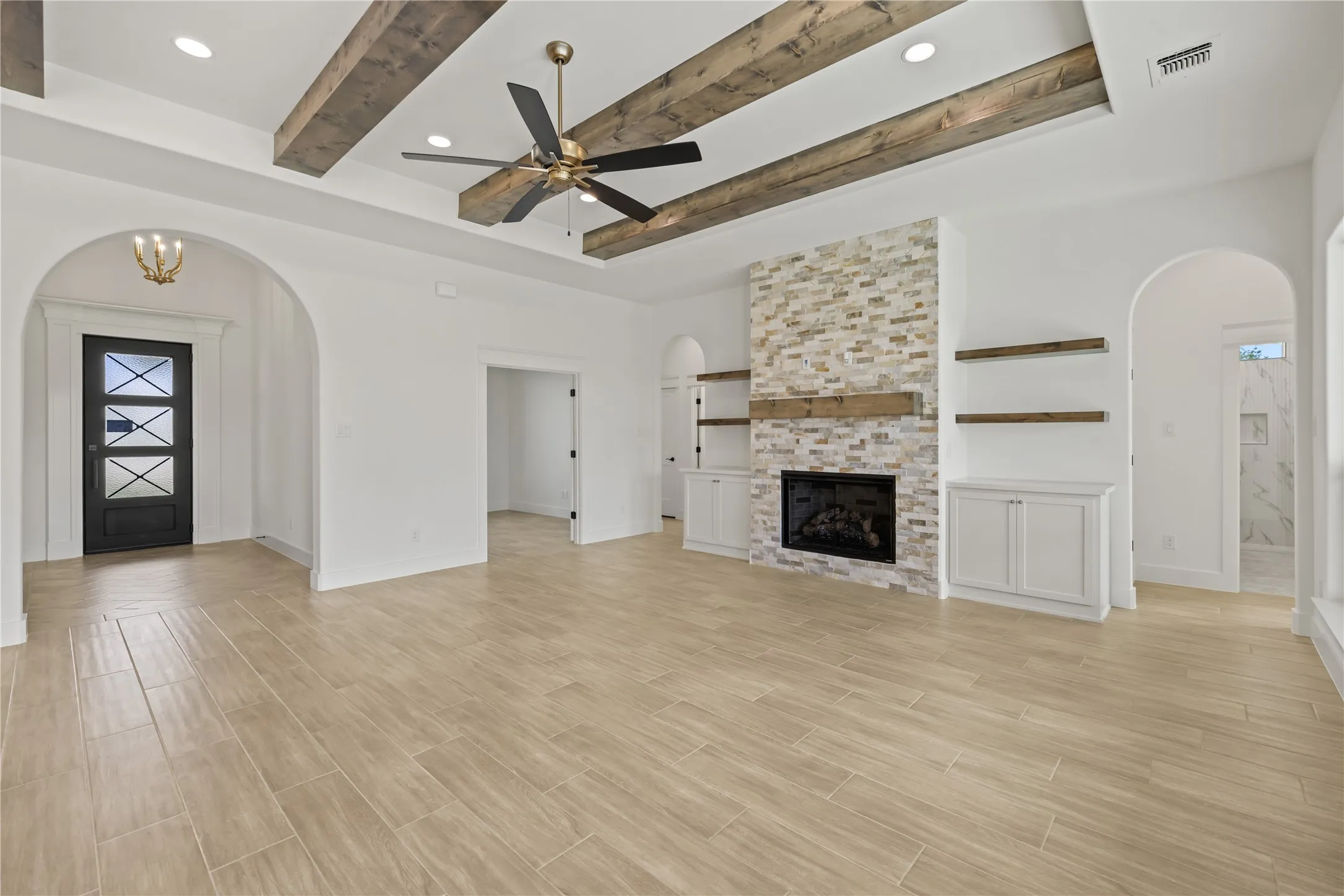 Wood-finish flooring, exposed ceiling beams, recessed lighting, stone-clad fireplace, and built-in cabinetry
