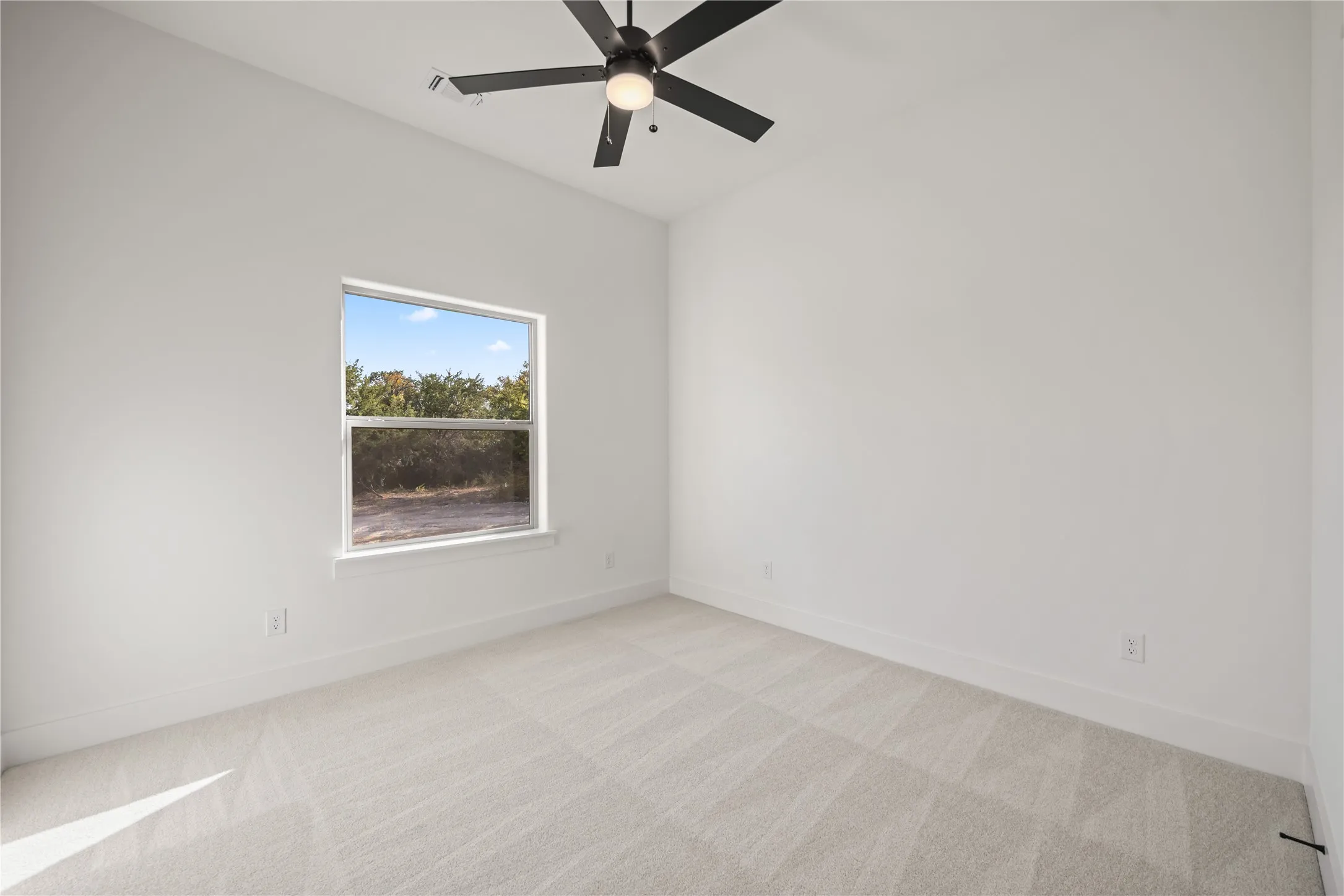 Recessed lighting, ceiling fan, white walls, light-toned carpet, and a large window