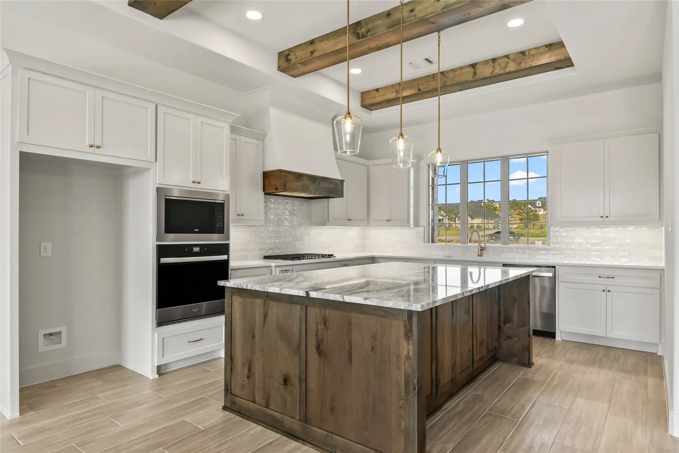 Kitchen featuring a large central island with a stone countertop, built-in stainless steel appliances, white cabinetry, and wood-finish flooring