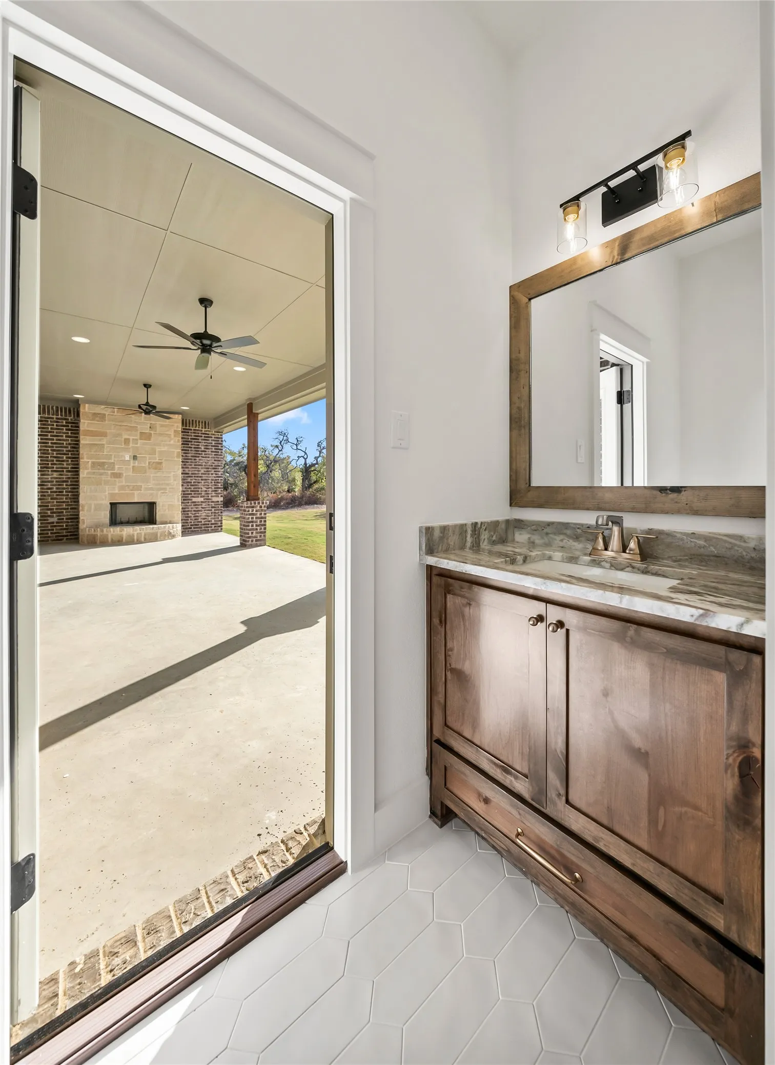 Wood-finish vanity with a stone countertop and a framed mirror