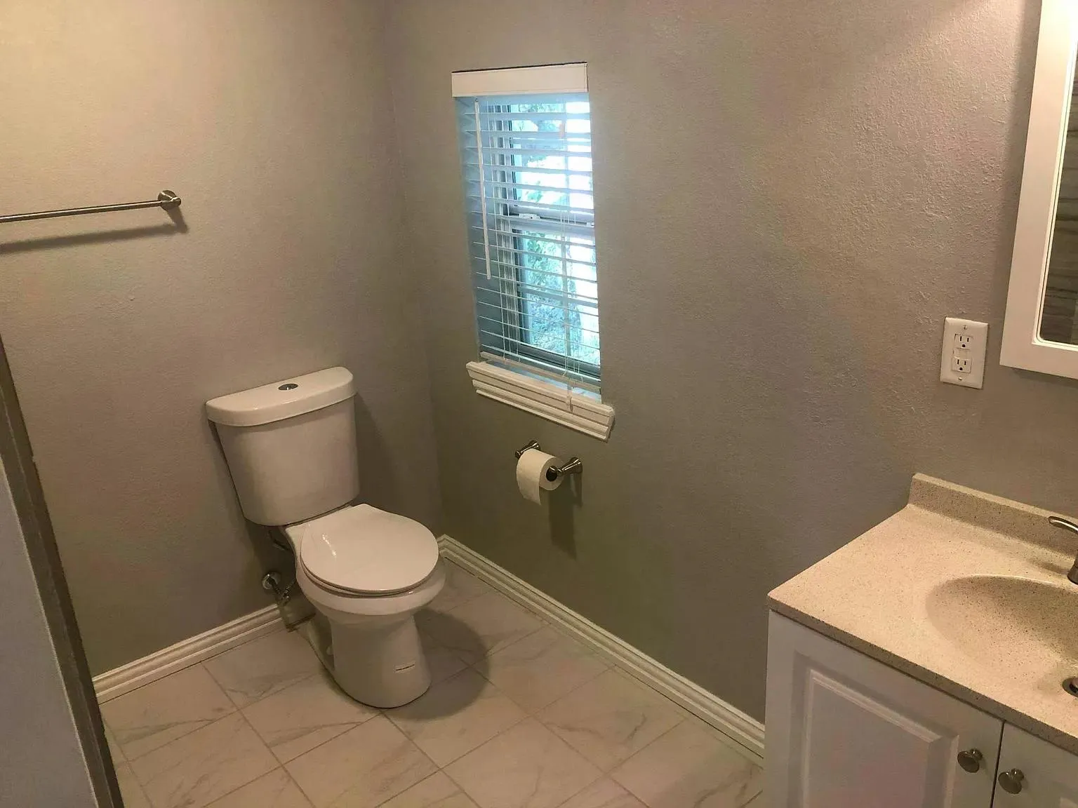 White vanity with a neutral-toned countertop and integrated sink