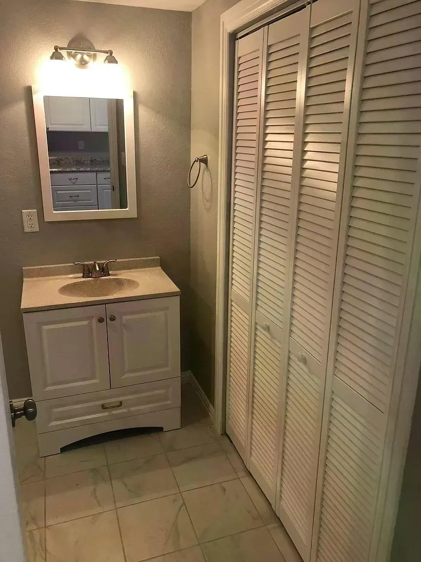 Elegant bathroom featuring a white vanity with dual-door cabinetry, ceramic sink, and brushed nickel hardware