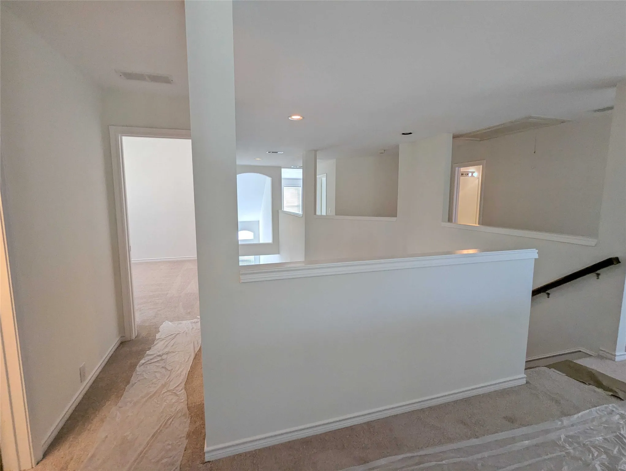 Upper level landing with carpeted flooring and white painted walls