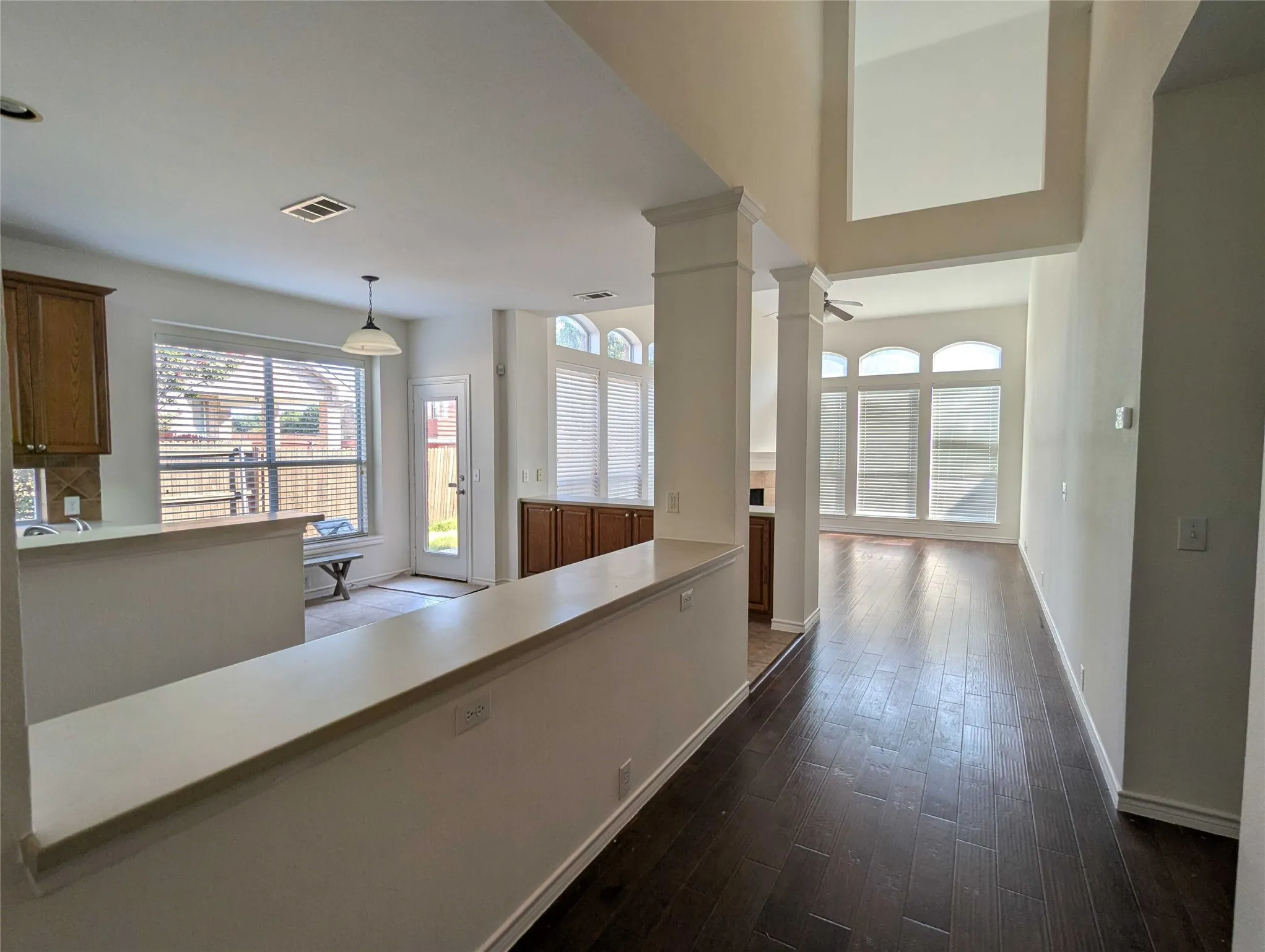 Dark wood-finish flooring throughout, columns with crown molding accents, and a dual-height ceiling