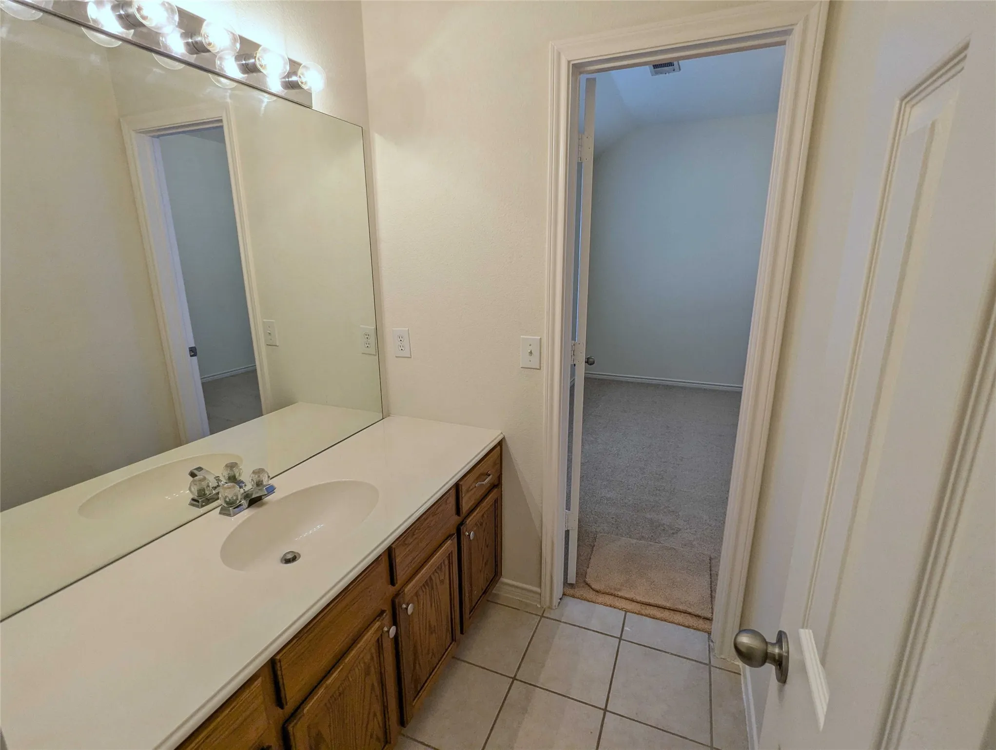 Vanity with dual oval sinks, wood-finish cabinetry, and a full-width mirror