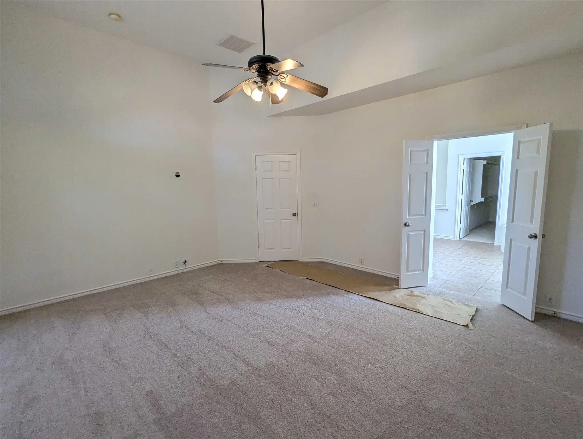 Vaulted ceilings with recessed lighting, ceiling fan with light kit, carpeted flooring, French doors, and a paneled interior door