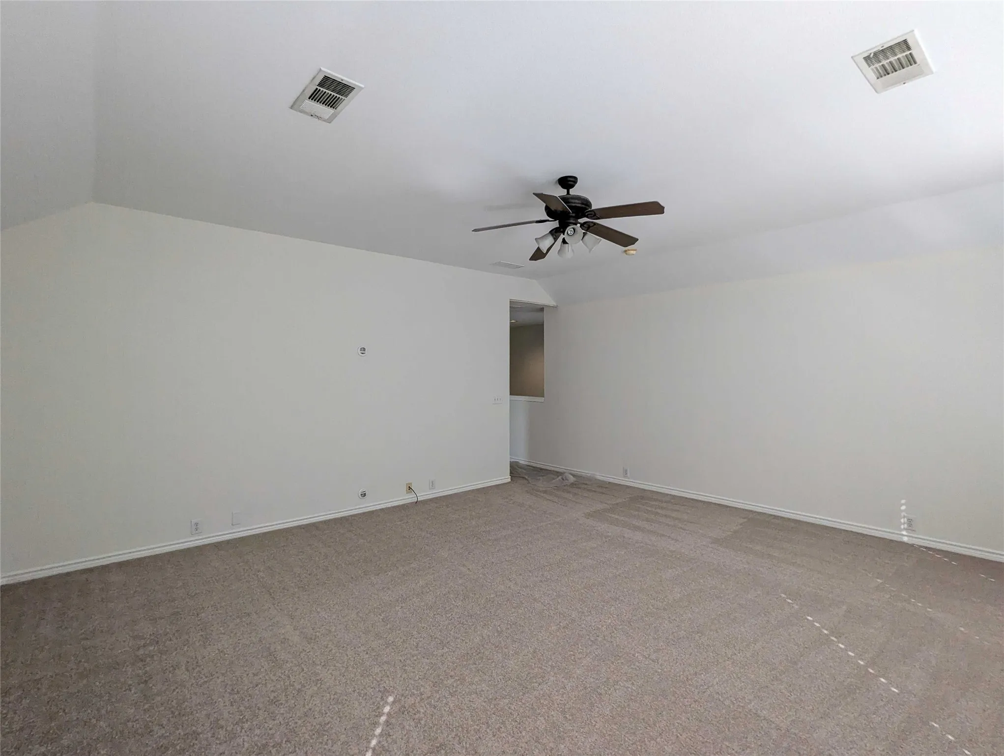 Carpeted room with a ceiling fan light fixture and recessed ceiling vents