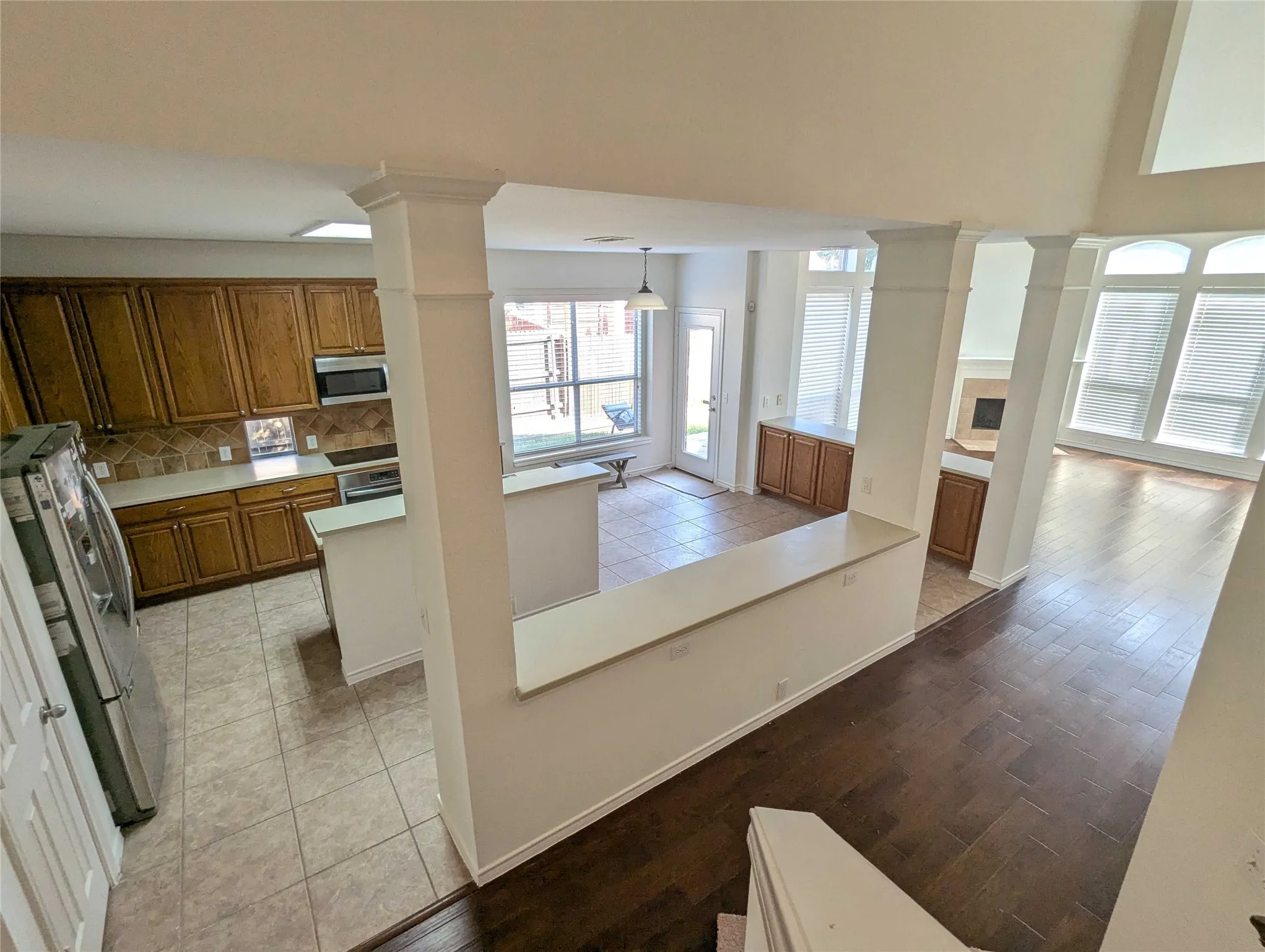 Open-concept living area with high ceilings, wood-finish flooring, and a fireplace