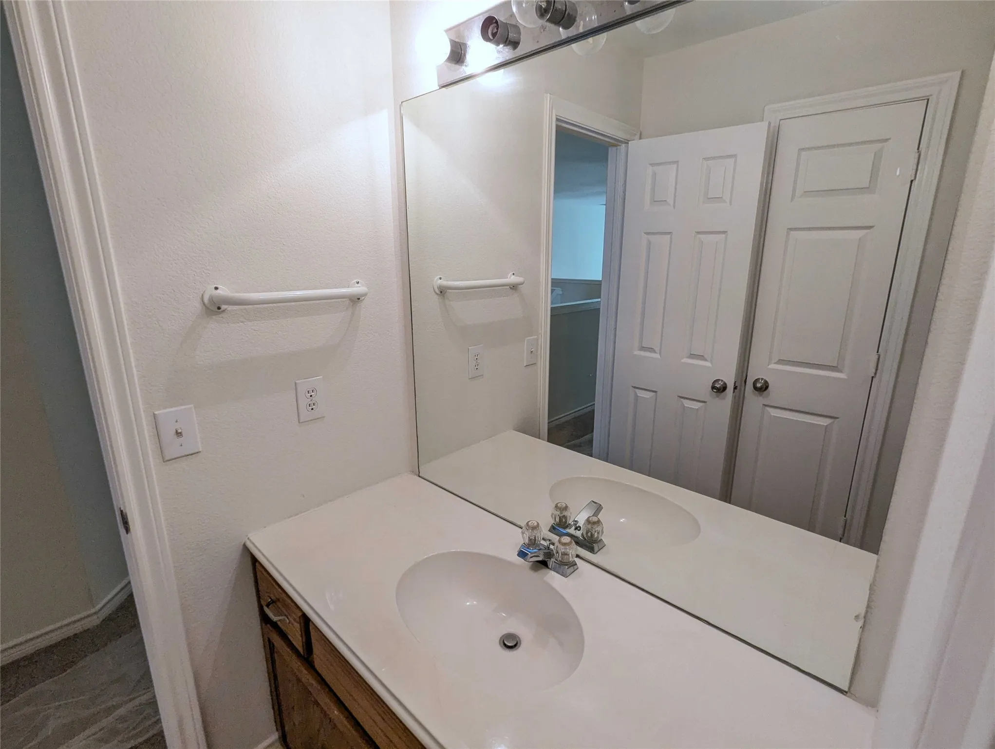 White countertop vanity with integrated sink and wood-finish cabinetry
