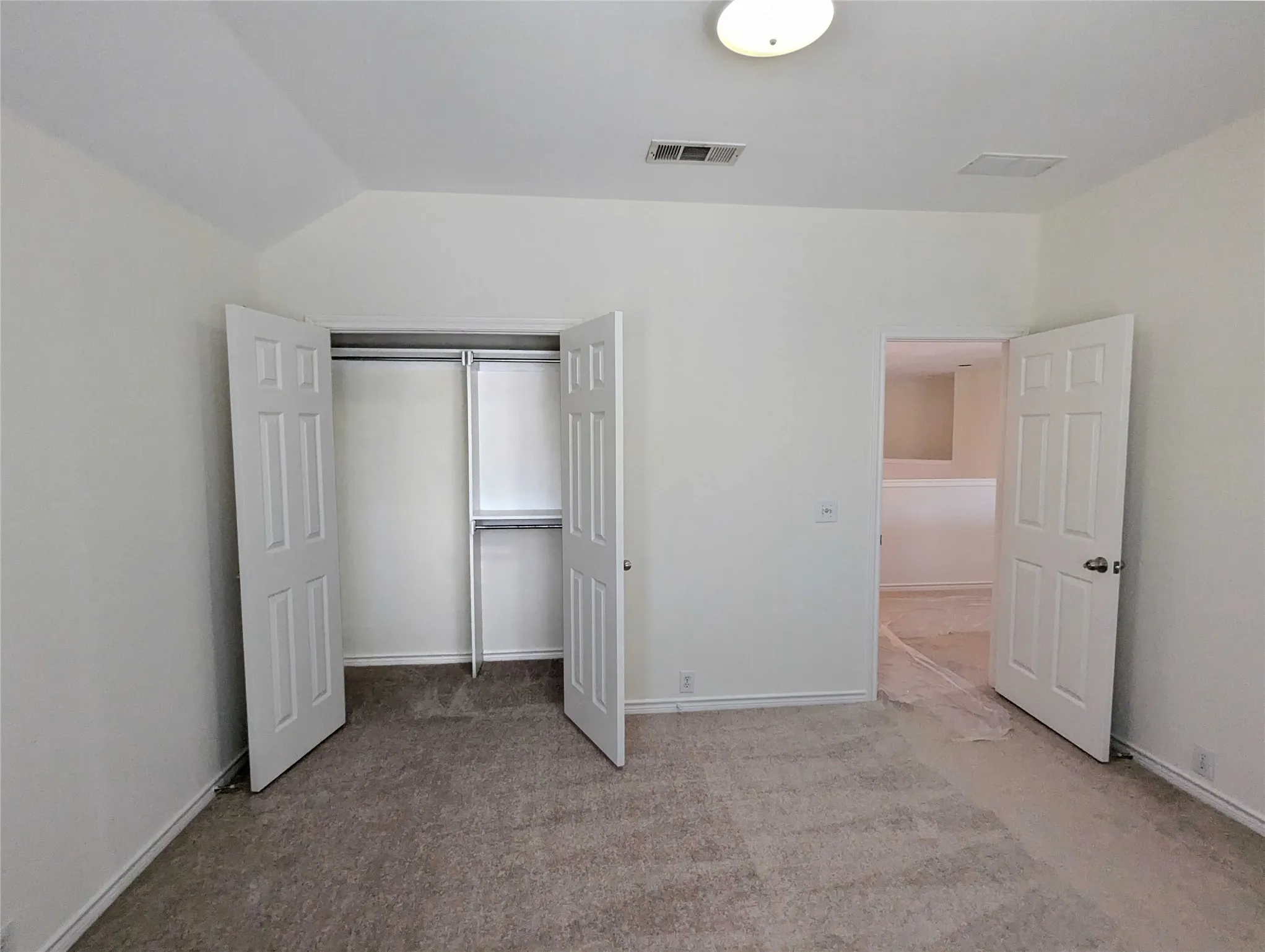 Neutral tone wall paint, textured carpet flooring, six-panel interior doors, ceiling-mounted light fixture, built-in closet shelving