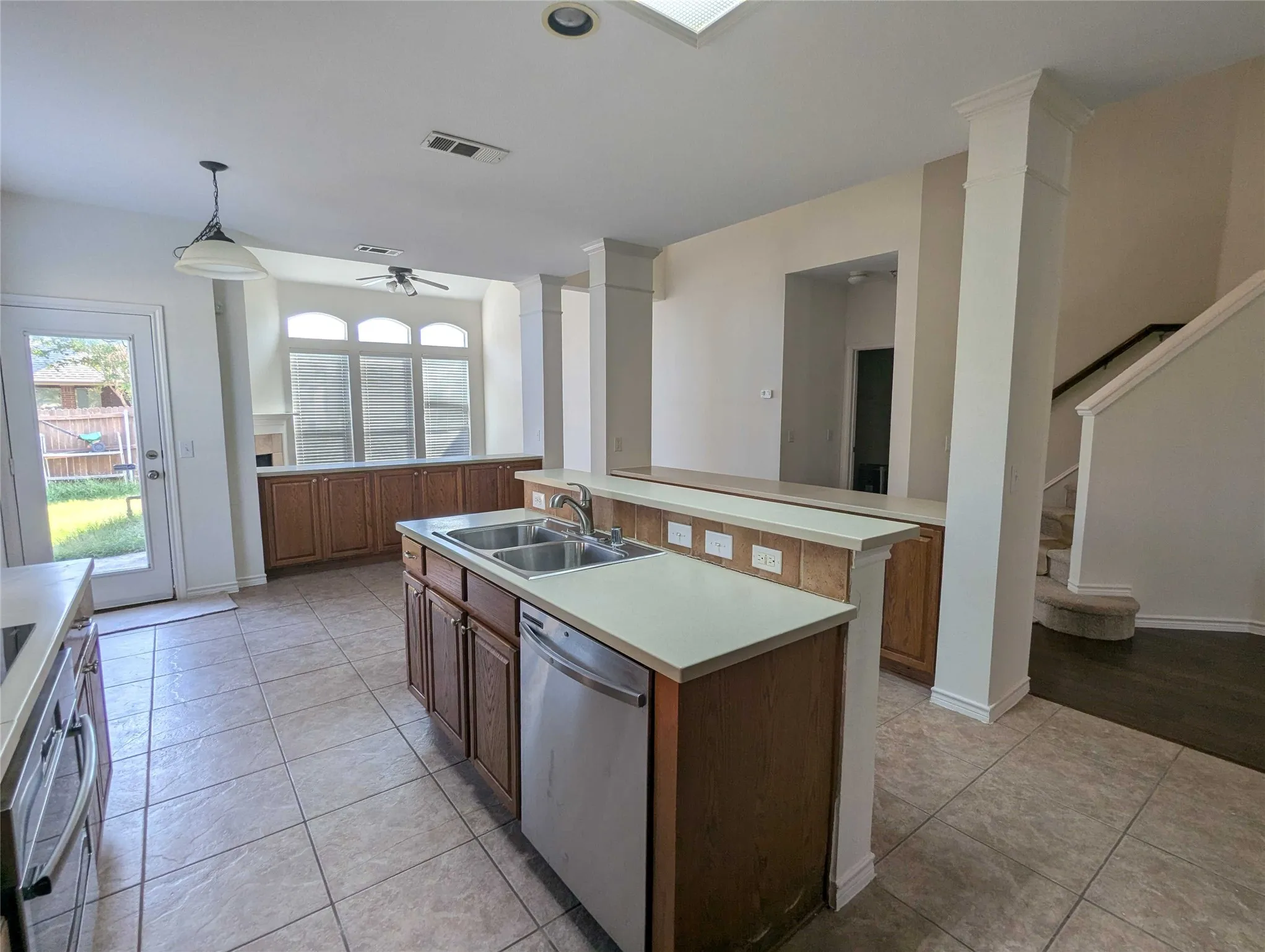 Kitchen featuring tile flooring, a center island with a double basin sink, and a dishwasher