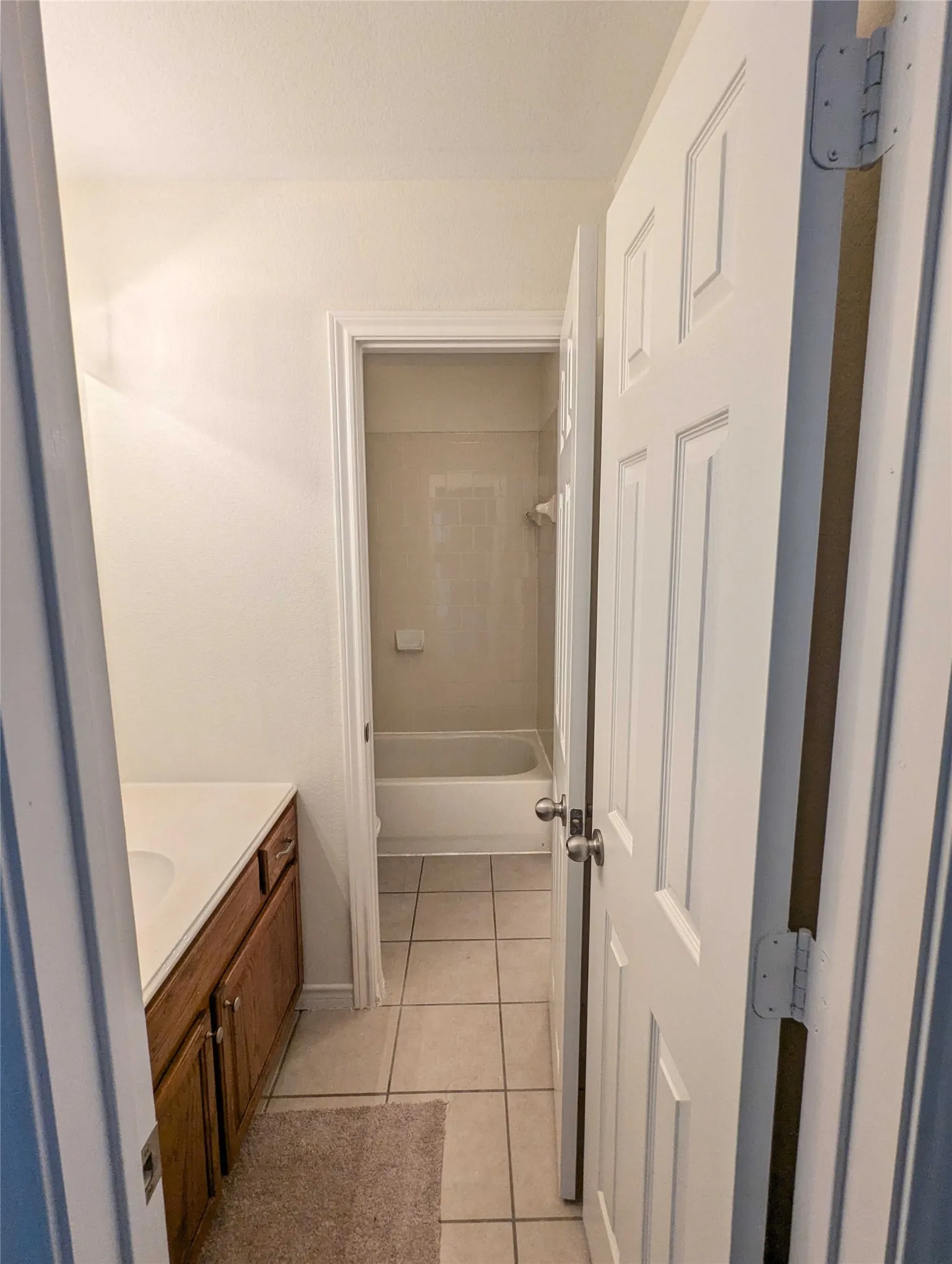 Bathroom featuring a wood-finish vanity with an integrated sink and tiled flooring