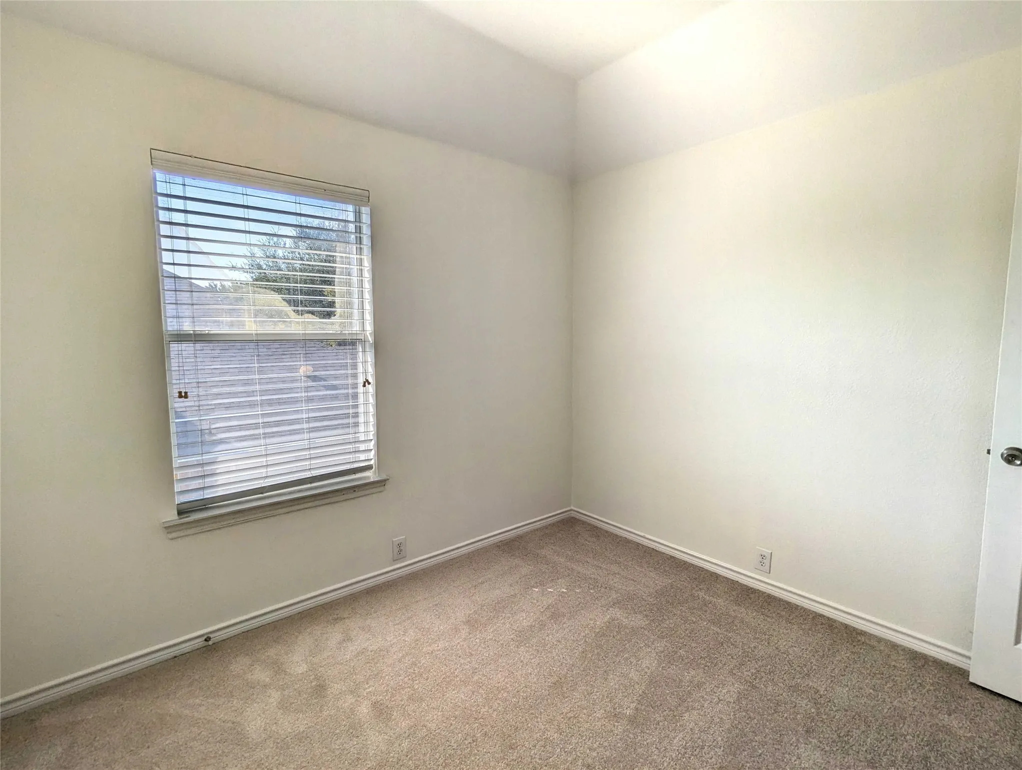 Recessed ceiling, window with blinds, light neutral-toned walls, and carpeted flooring