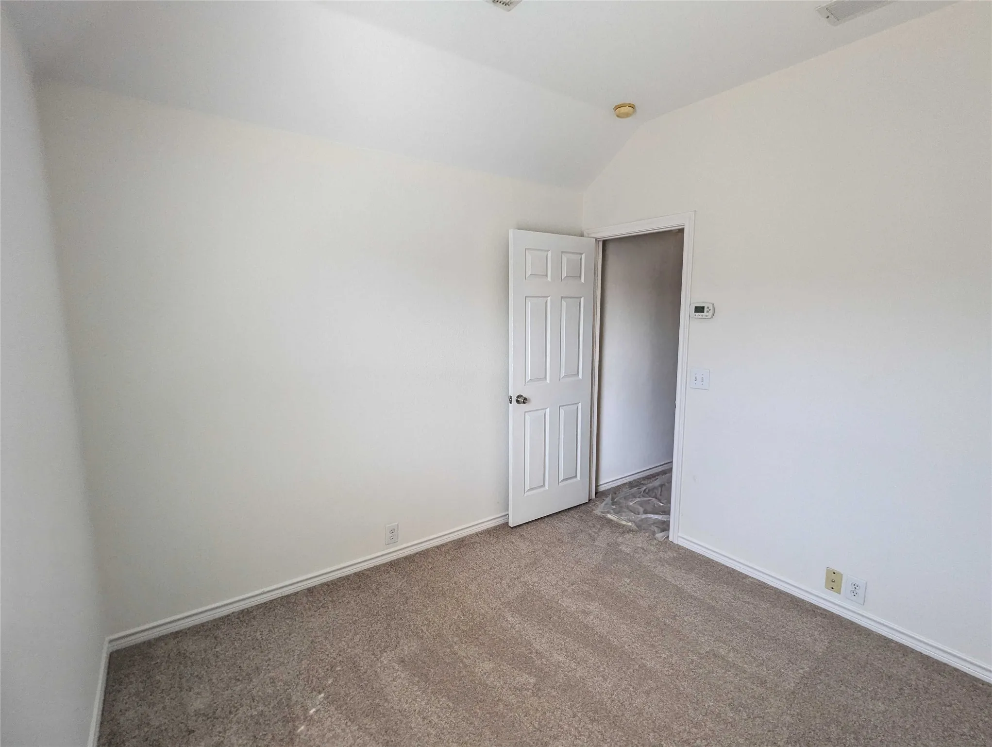 Neutral-toned carpet flooring, white walls, and a vaulted ceiling