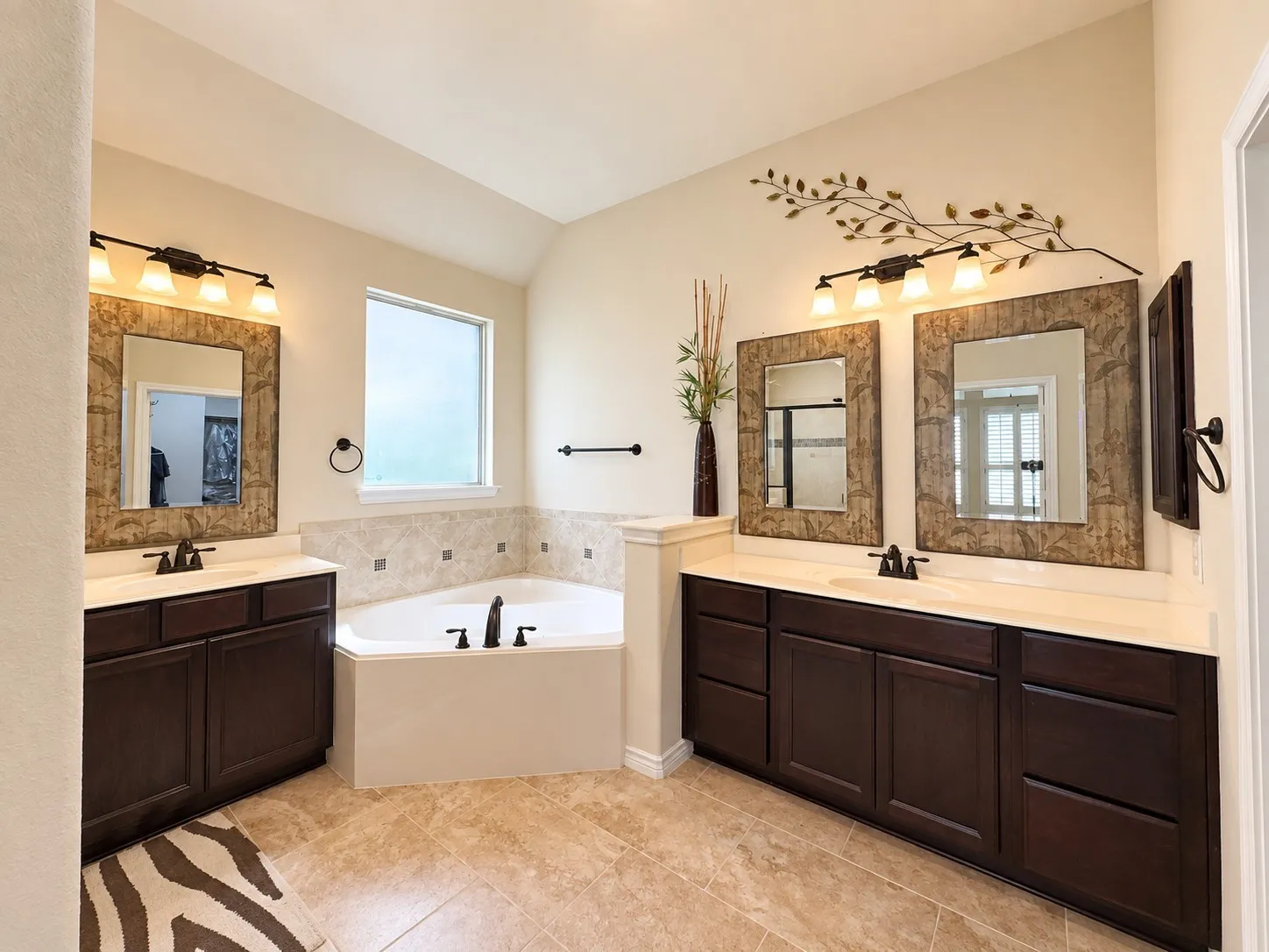 Dual vanity with dark wood-finish cabinetry and light countertops, corner soaking tub, and tile flooring