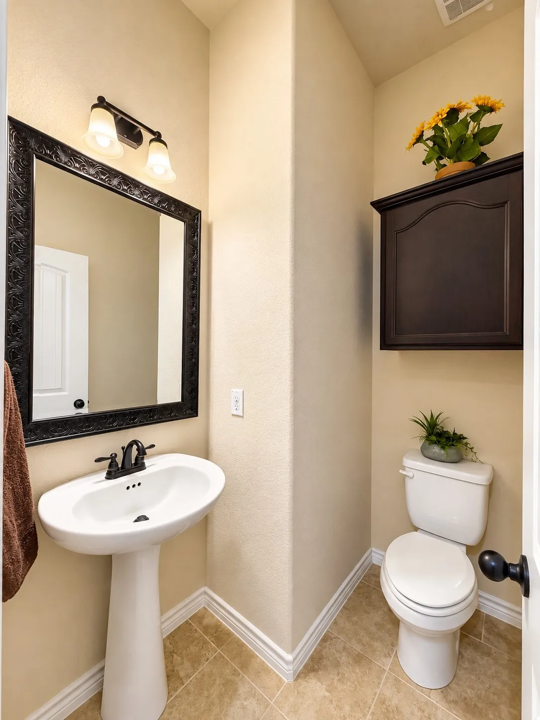 Pedestal sink with oil-rubbed bronze faucet, decorative framed mirror, built-in wall cabinet, and tiled flooring