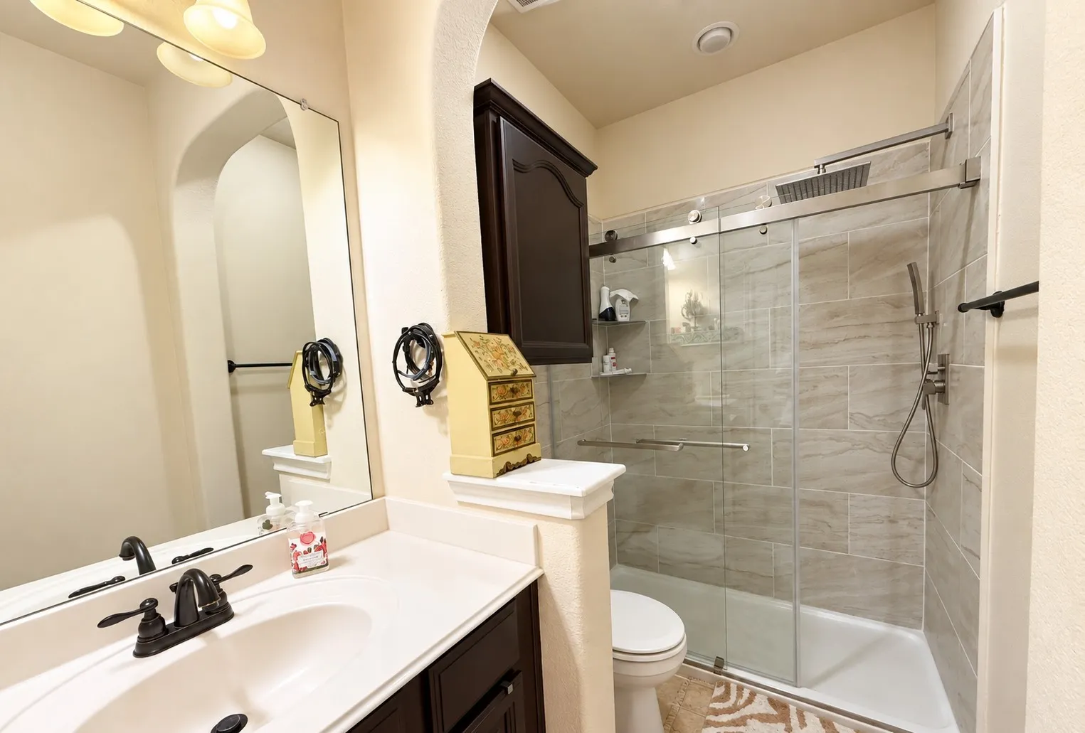 Vanity with integrated sink, dark wood-finish cabinetry, and matte black faucet