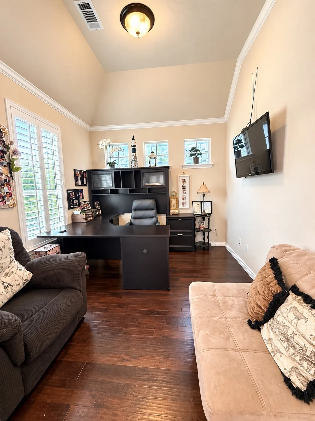 Vaulted ceiling with an attached light fixture, wood-finish flooring, and white window shutters
