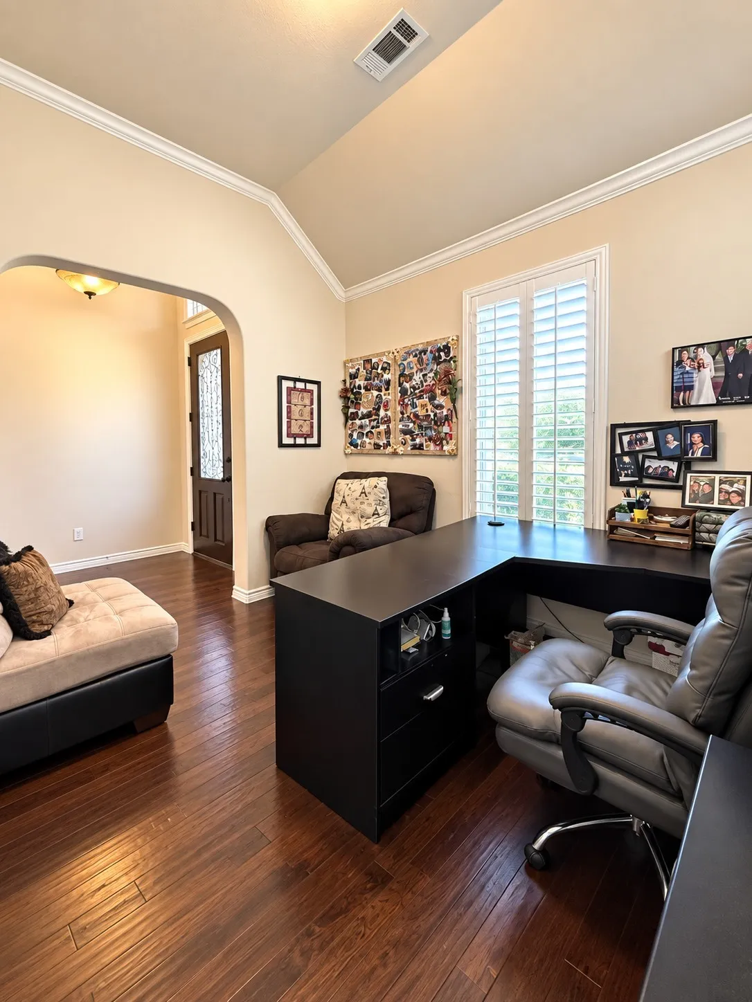 Hardwood flooring, vaulted ceiling, crown molding, arched entryway, and plantation shutters