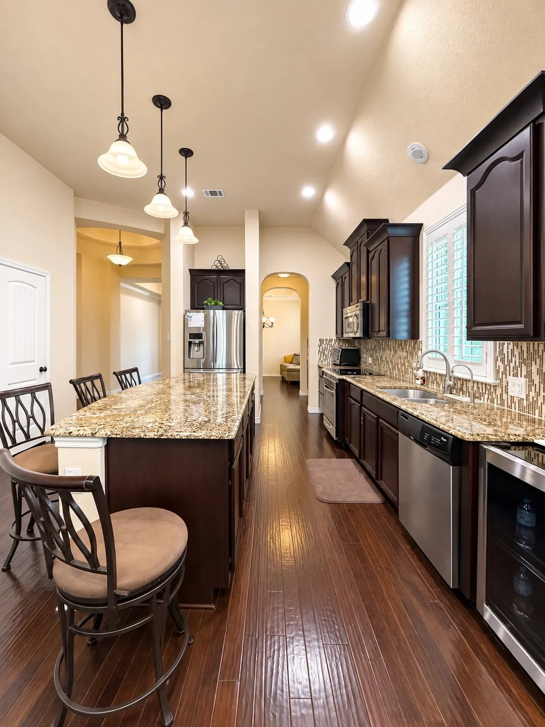 Kitchen featuring wood-finish flooring, granite countertops, dark wood cabinetry, stainless steel appliances, and recessed lighting