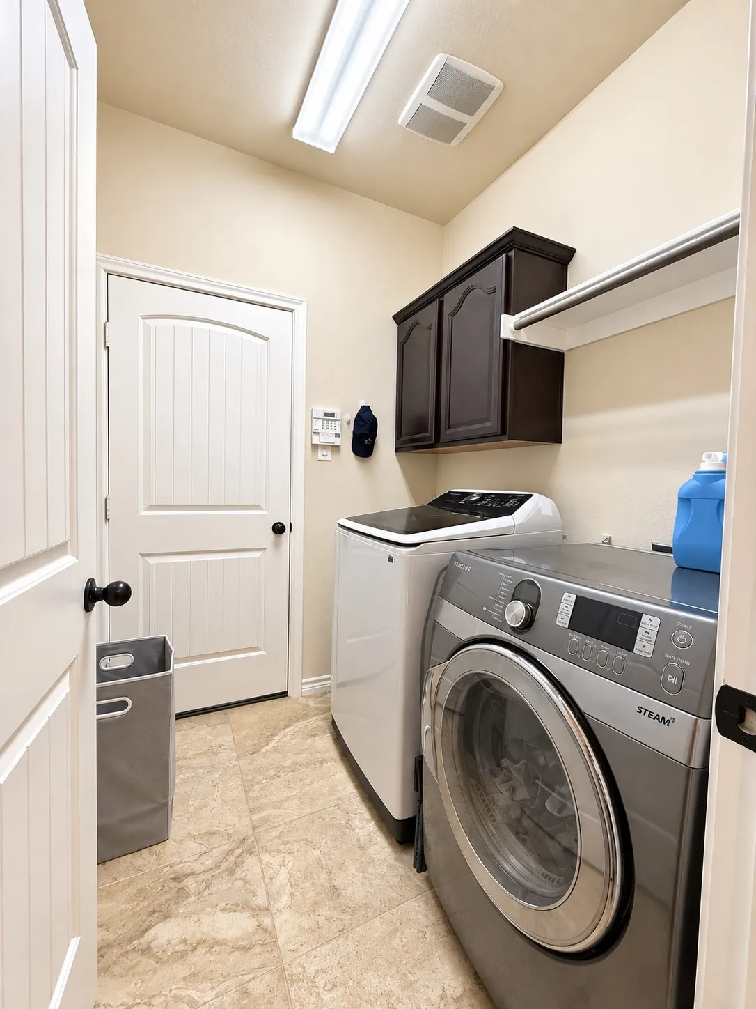 Laundry area featuring tile flooring, dark wood-finish cabinetry, and a built-in shelf