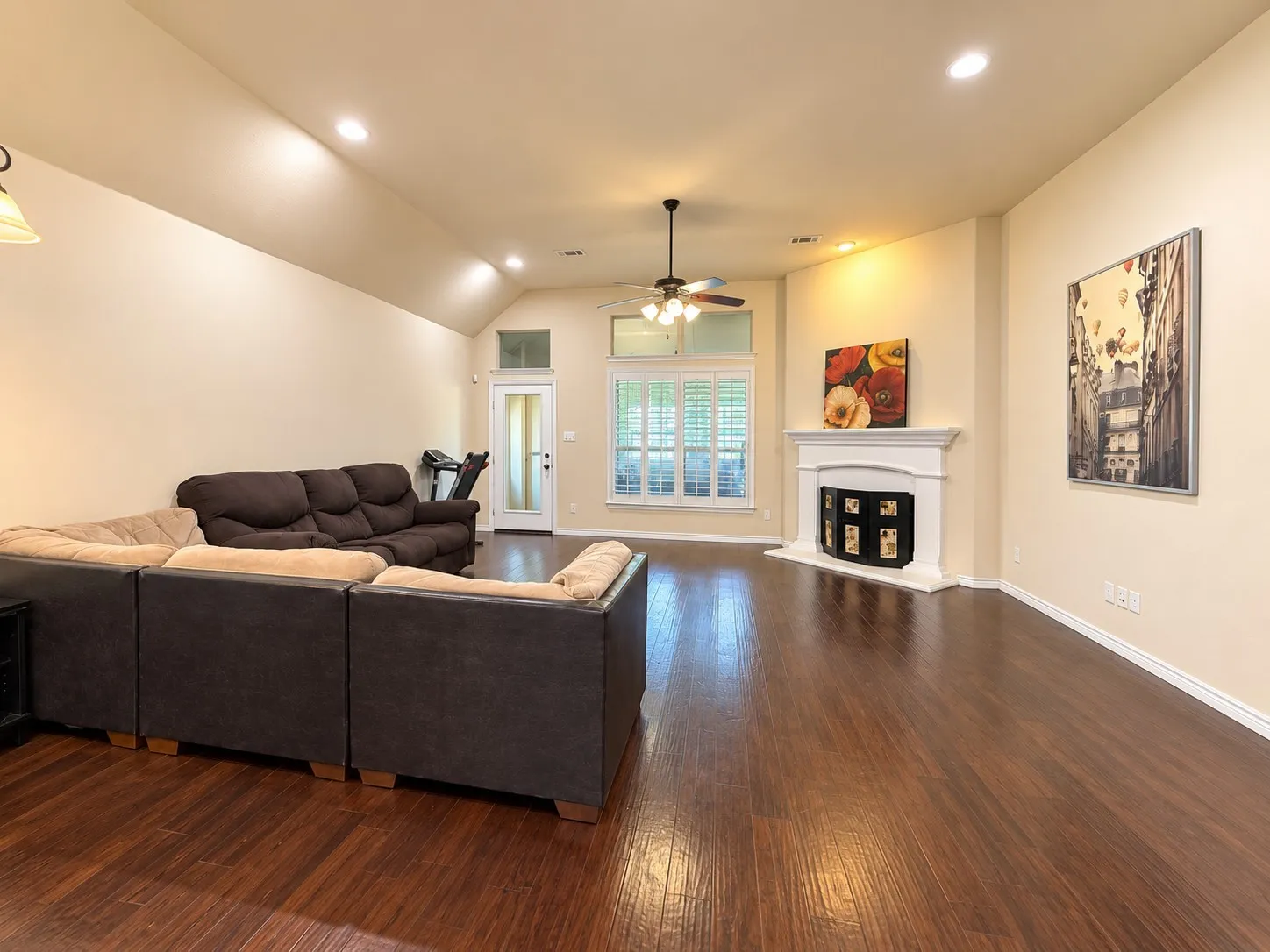 Vaulted ceiling with recessed lighting, wood-finish flooring, white fireplace mantel, and ceiling fan