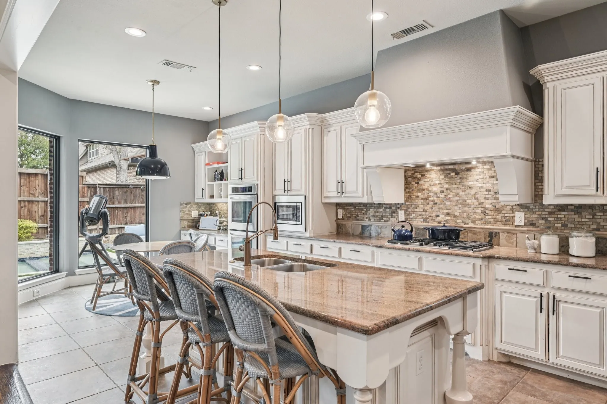 Kitchen featuring white cabinetry, built-in appliances, a large island with an integrated sink, a mosaic tile backsplash, and recessed lighting