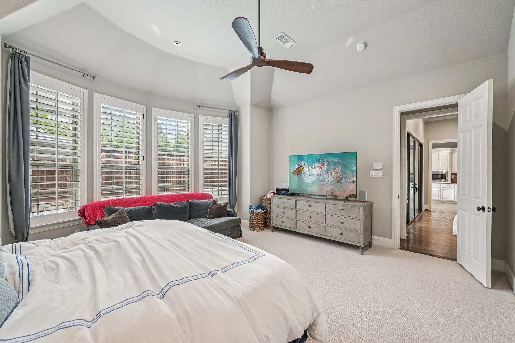 Bay windows with plantation shutters, ceiling fan with light fixture, recessed lighting, and neutral carpeting