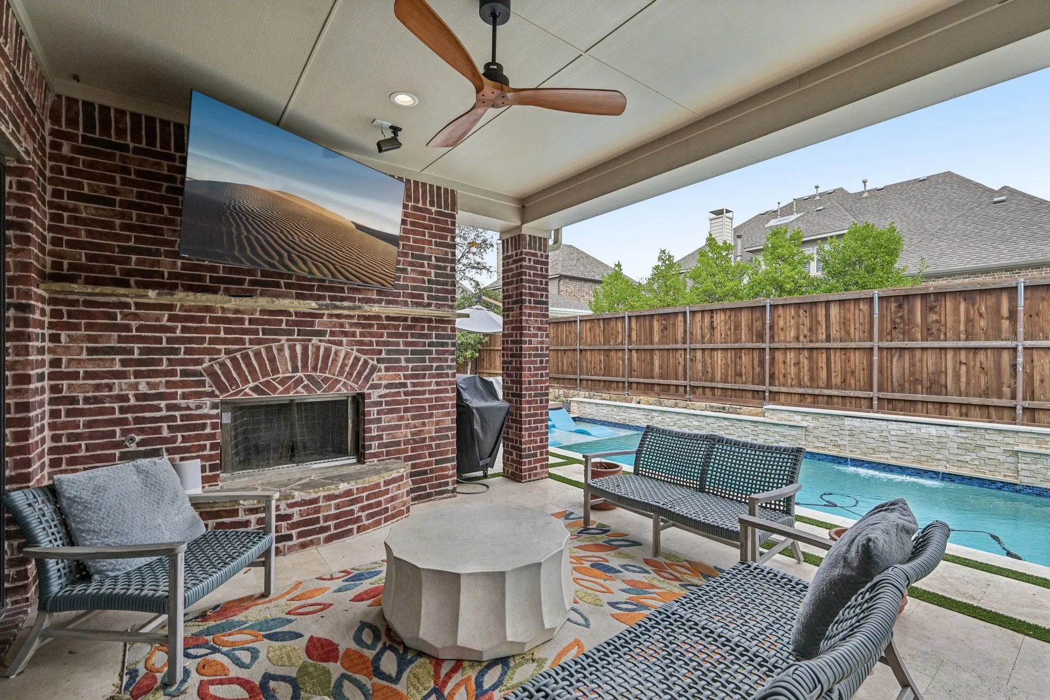 Covered patio with a brick fireplace, ceiling fan, and recessed lighting