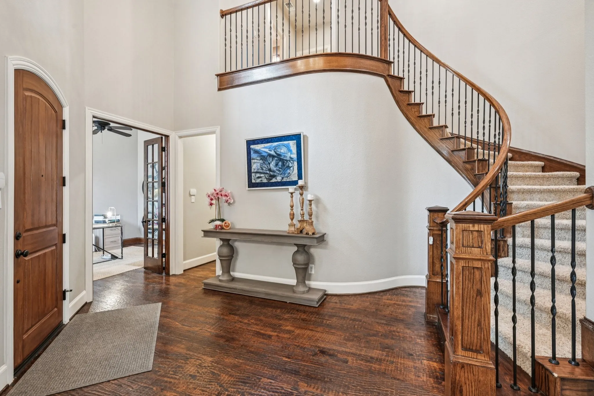 Grand entry featuring a curved staircase with wood and wrought iron balusters, wood-finish flooring, and double french doors