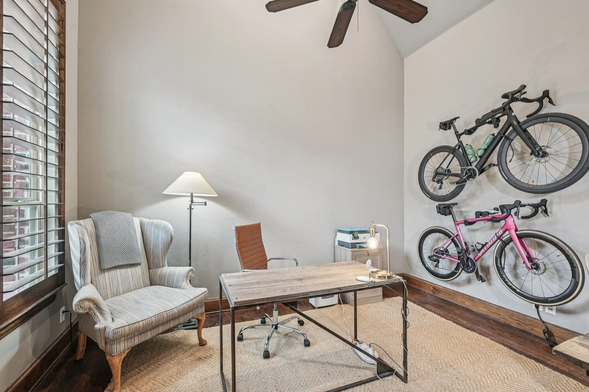 Vaulted ceiling with a ceiling fan, wood-finish flooring, plantation shutters, and a woven area rug