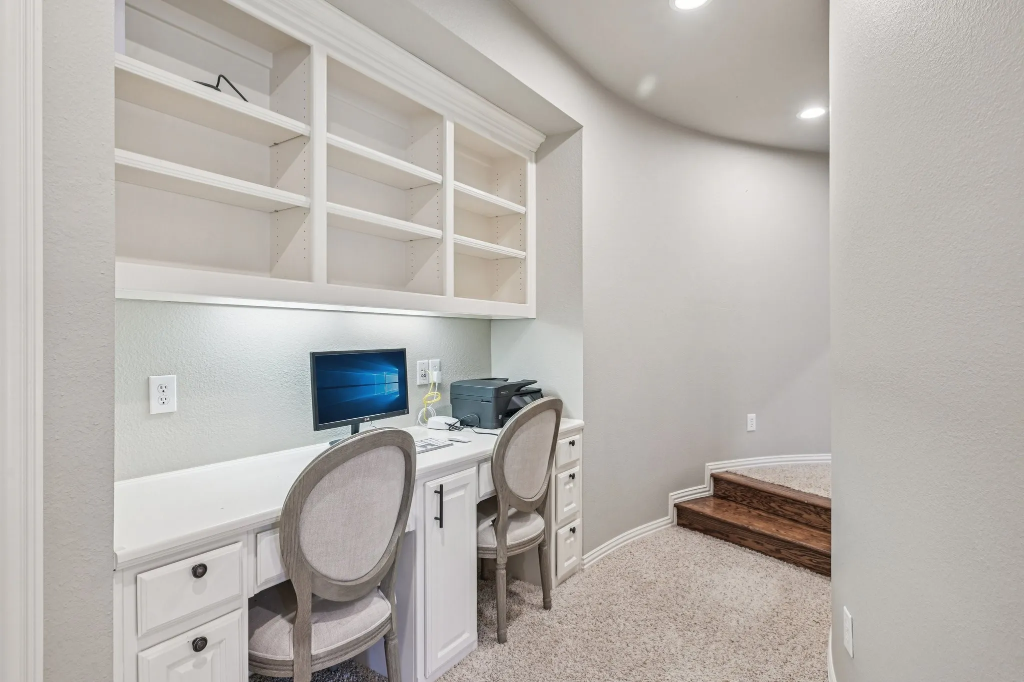 Built-in desk with overhead shelving, under-cabinet lighting, cabinet storage, and carpet flooring