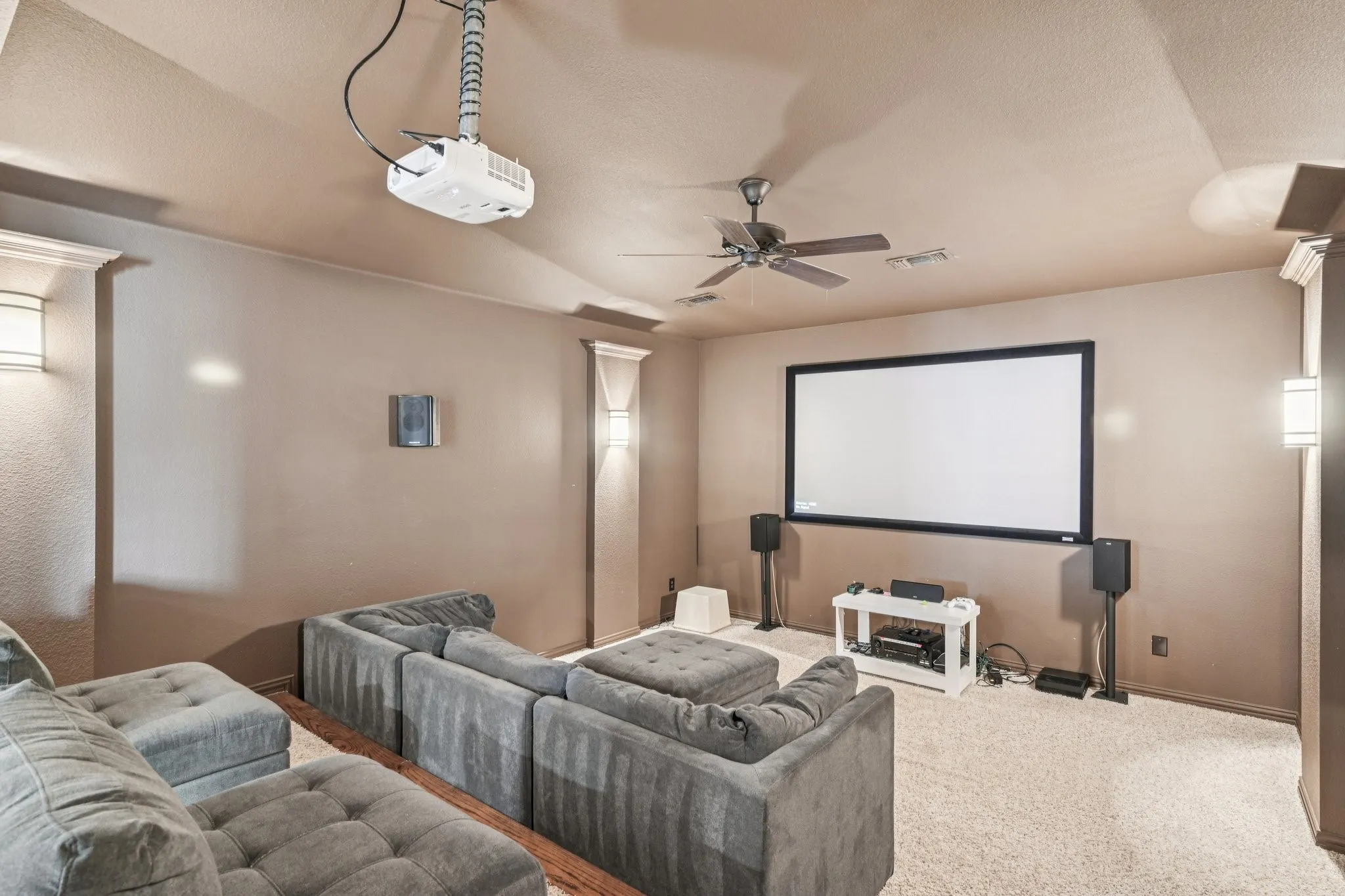 Projection screen with ceiling-mounted projector, integrated ceiling fan, recessed lighting, and wall sconces