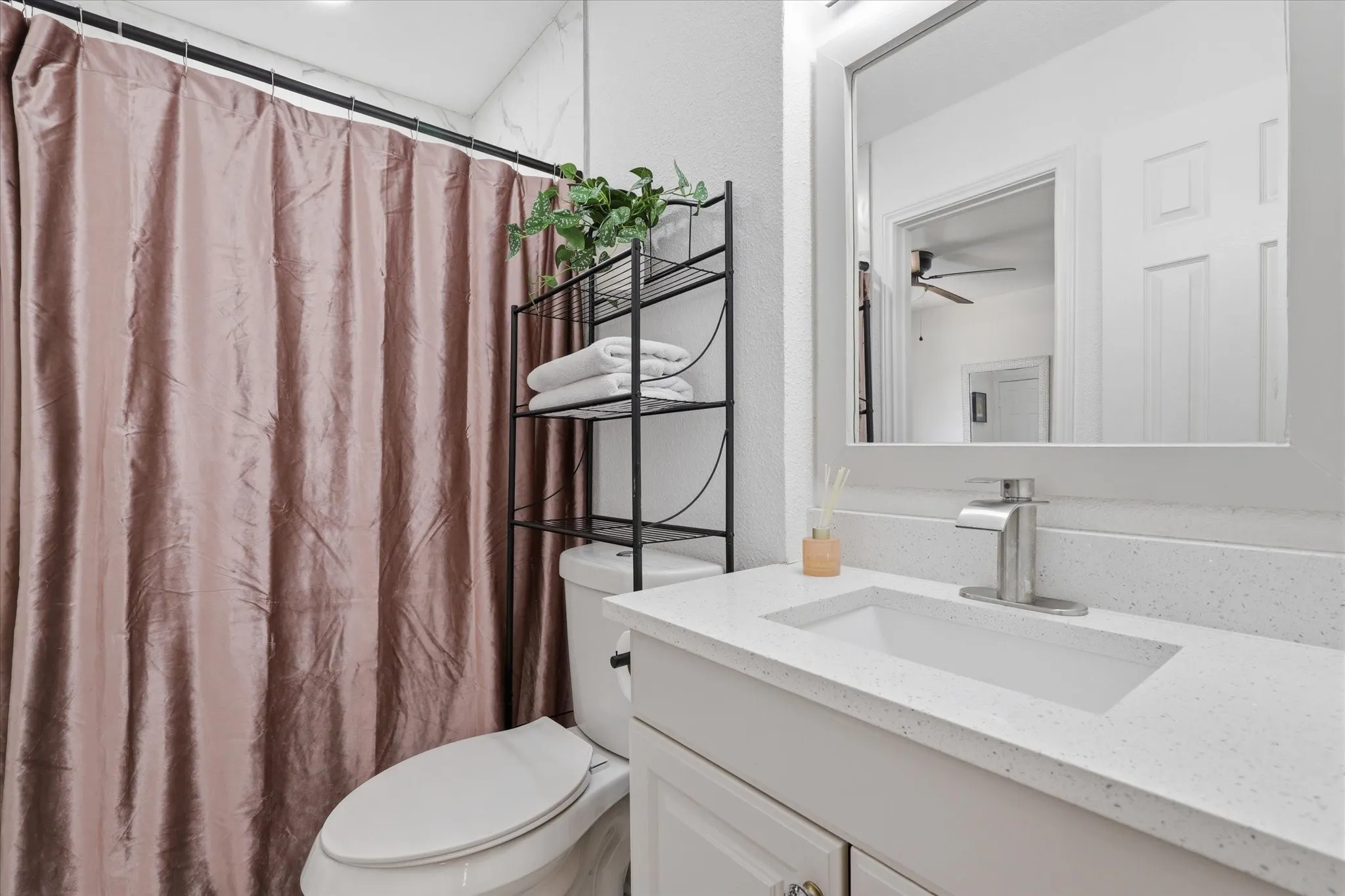 White vanity with a built-in rectangular sink, light-colored countertop, and brushed nickel faucet