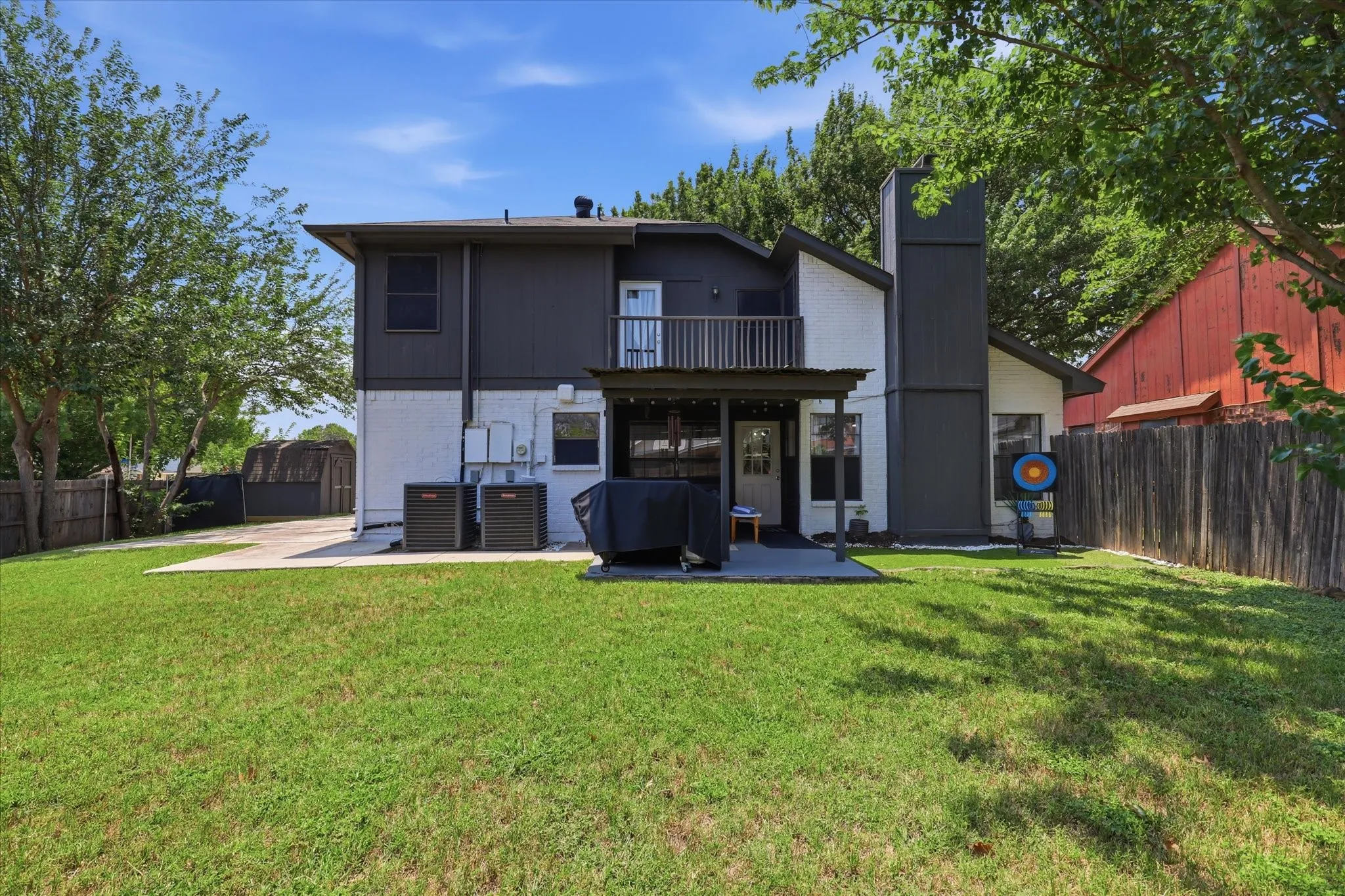 Expansive backyard featuring a patio, second-story balcony with railing, and a privacy fence