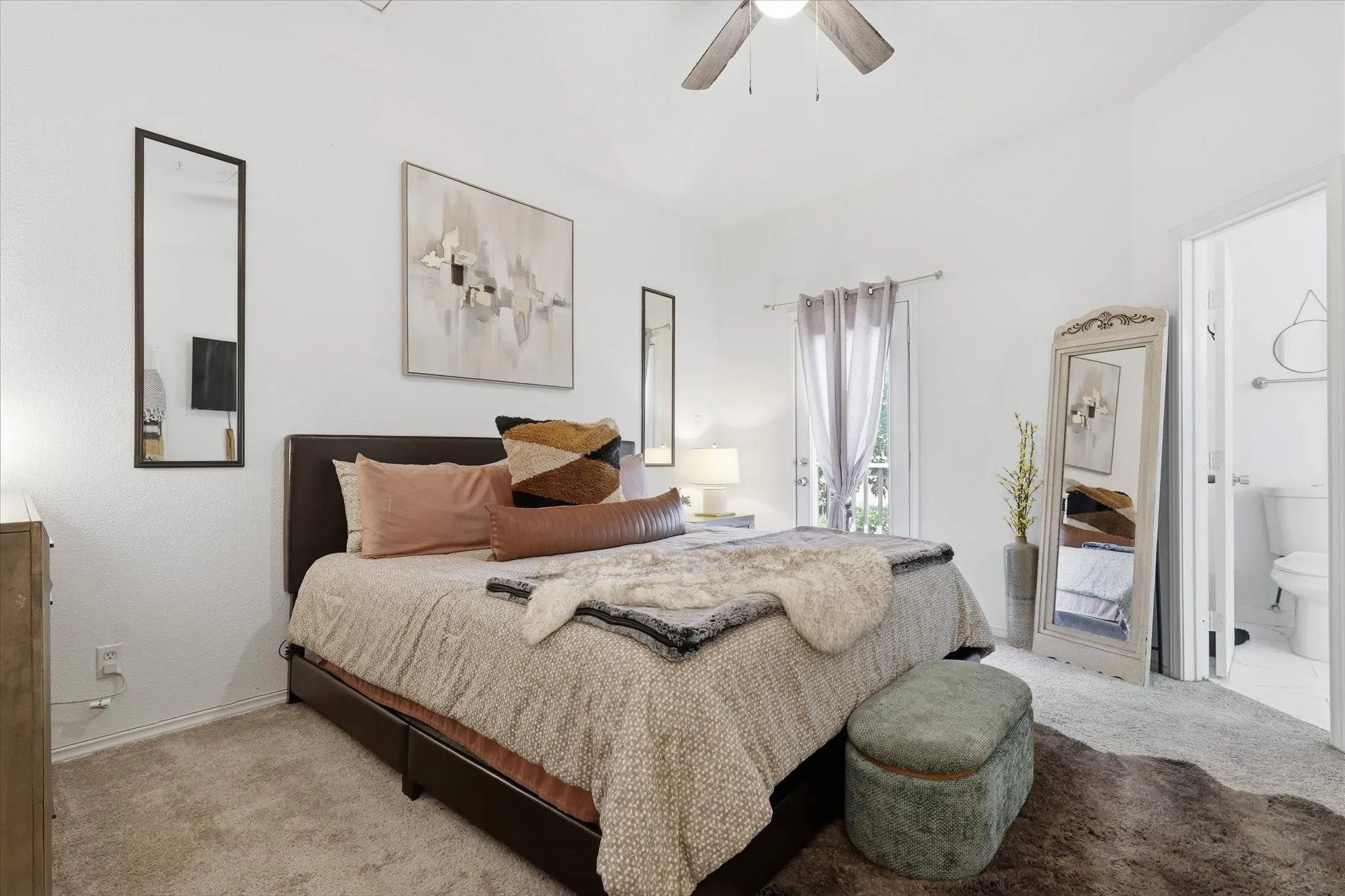 Carpeted bedroom featuring a ceiling fan, white walls, and a private door to a full bathroom