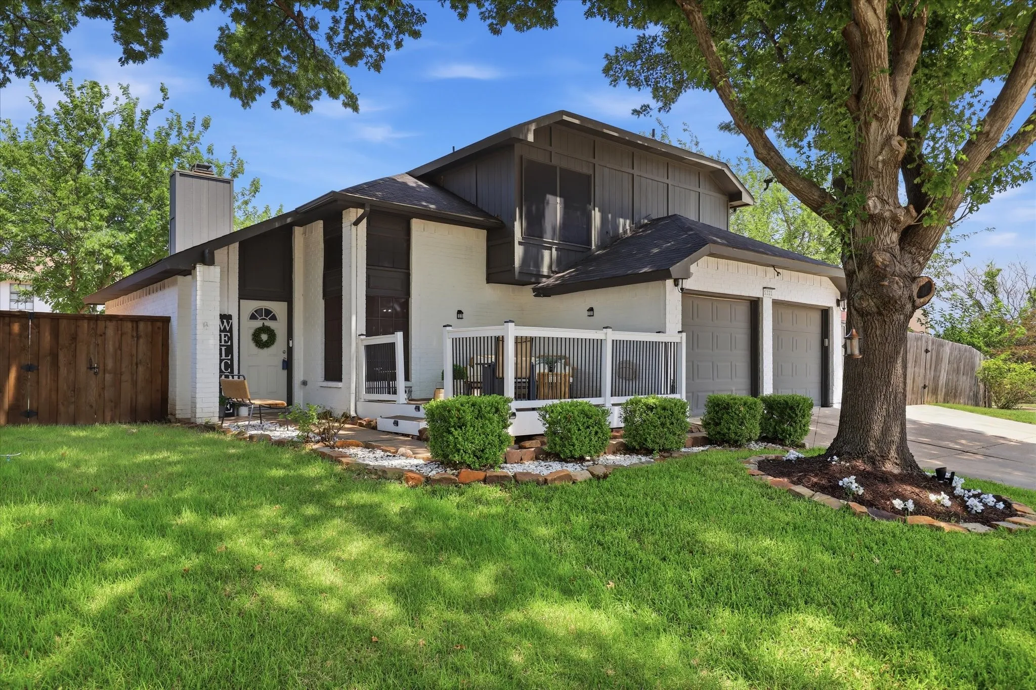 White brick exterior with dark trim accents and a partial wood fence