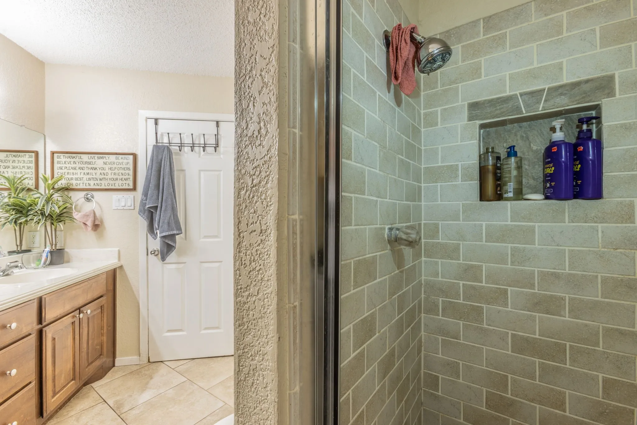 Tile shower with built-in niche, chrome showerhead, and glass enclosure