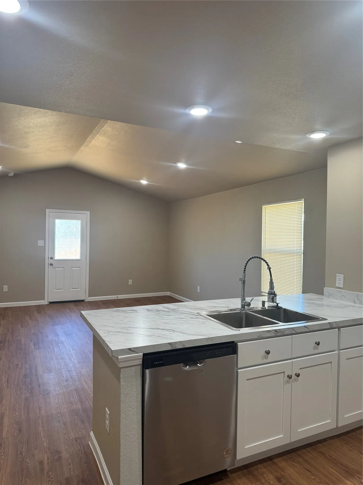 Kitchen island with a dual basin sink, pull-down faucet, and a built-in stainless steel dishwasher