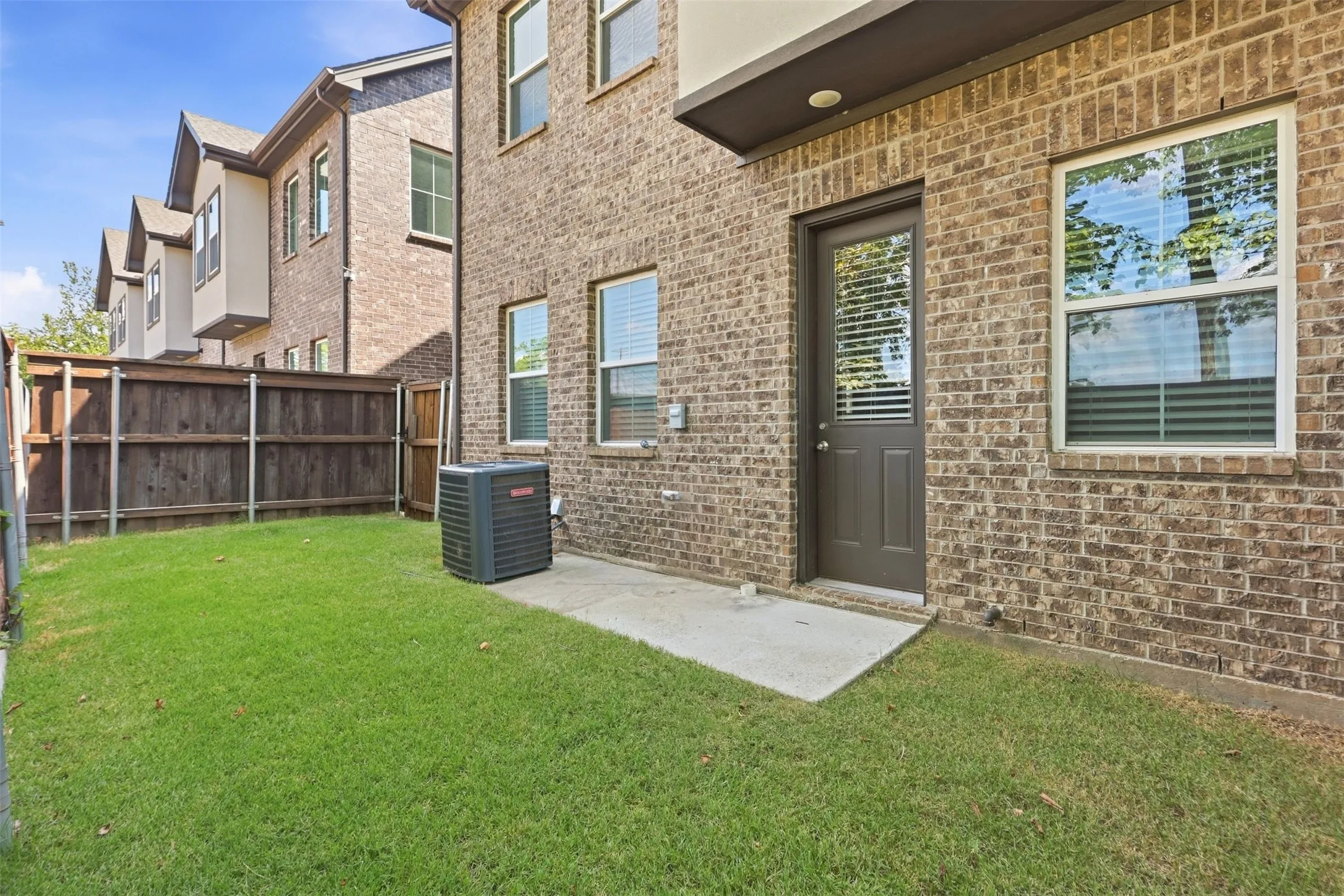 Brick exterior with a grass yard, privacy fencing, and a concrete patio