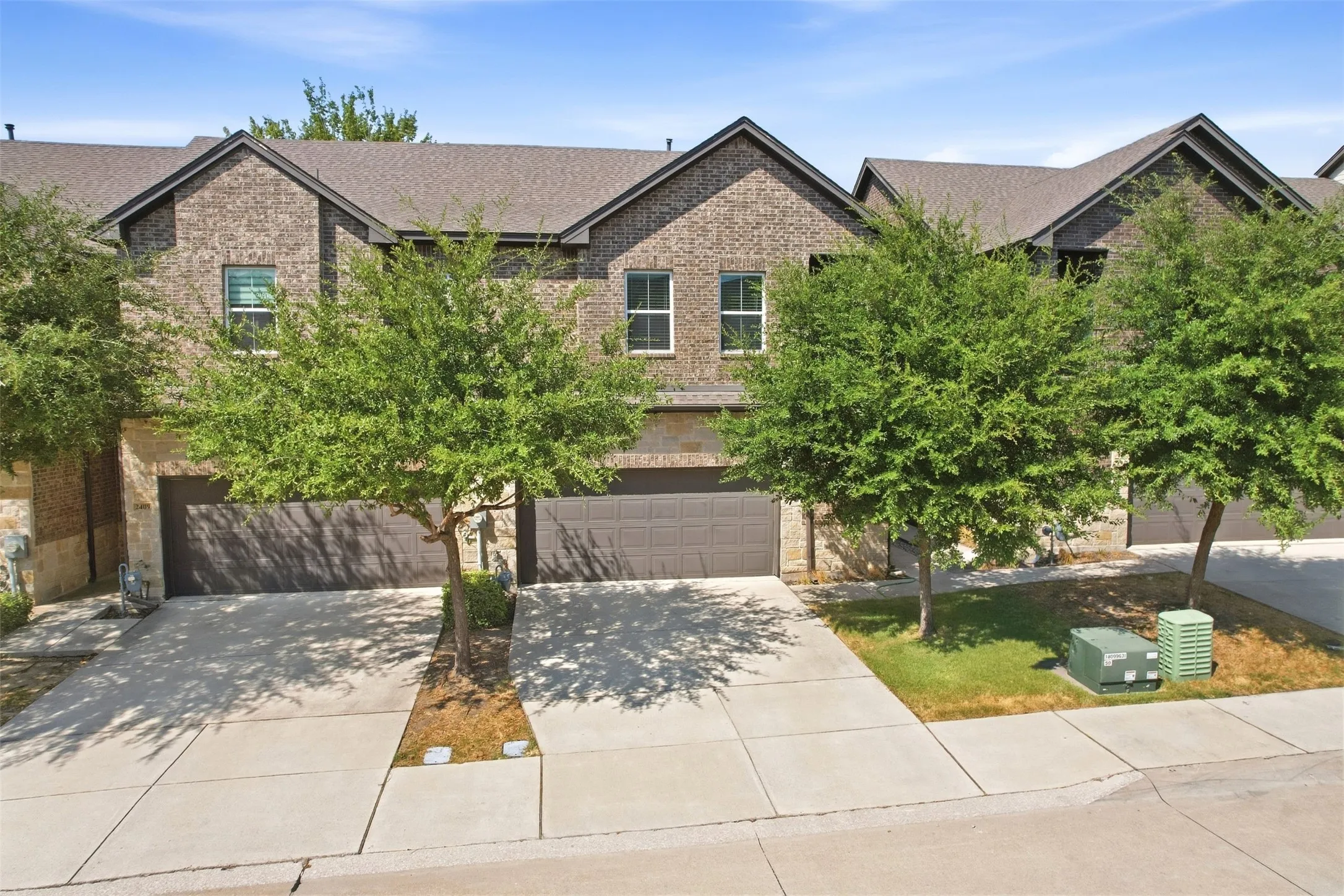 Brick and stone exterior with a gabled roofline, multiple windows, and integrated garages