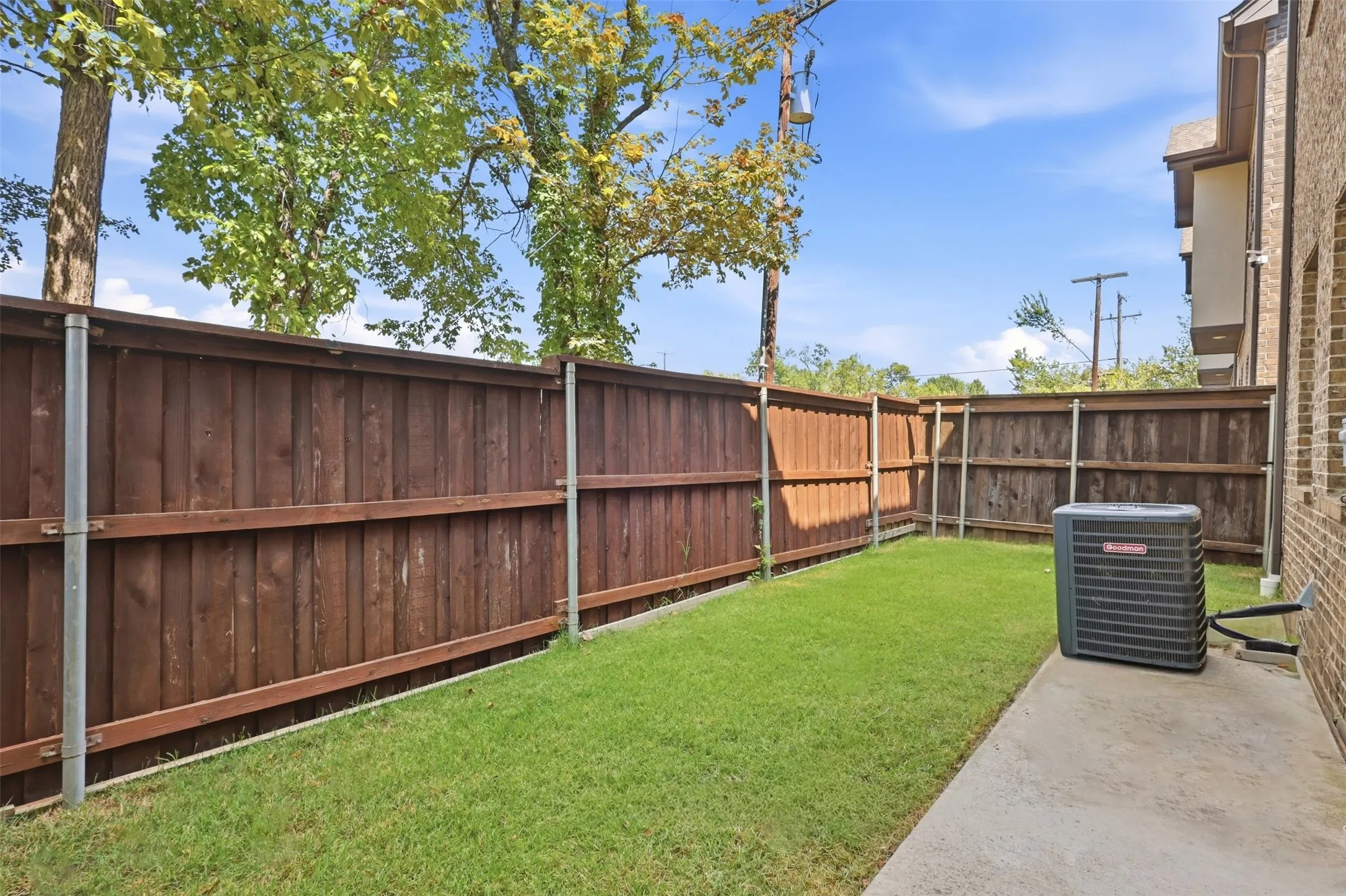 Private outdoor space featuring wood privacy fencing, green lawn, and concrete patio